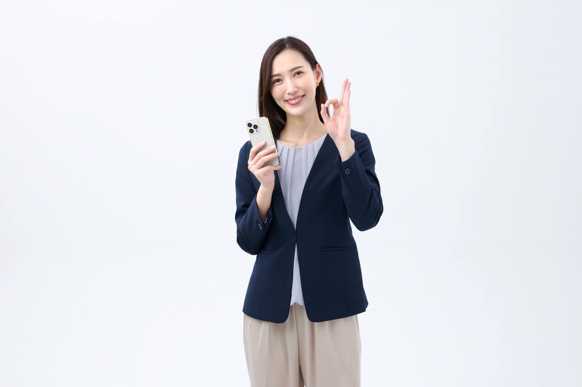 OKサインするスマホを持つ女性