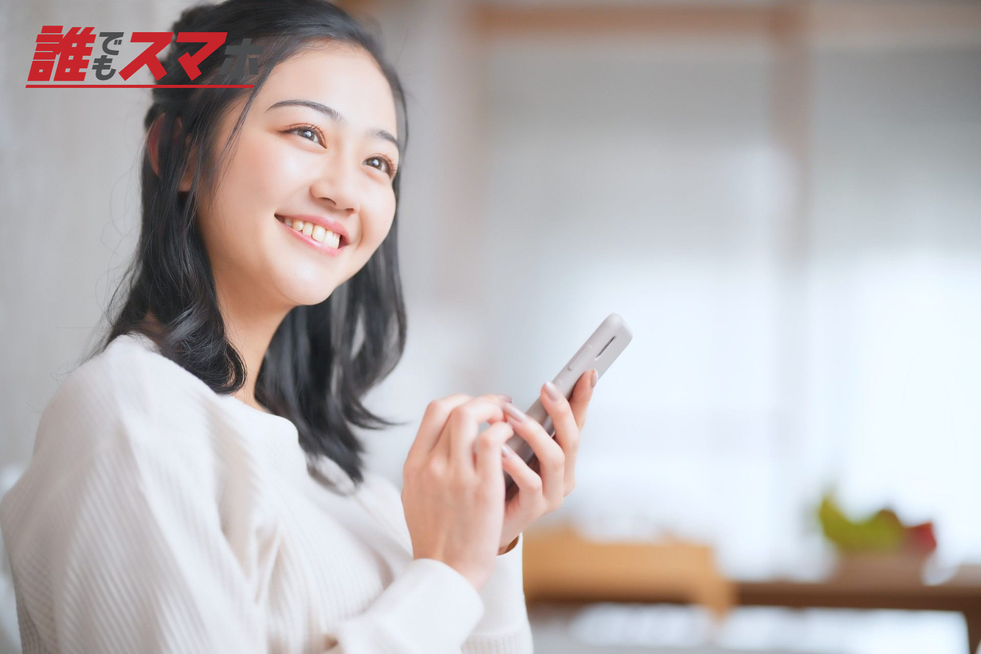 スマホを持ち笑顔で見つめる女性