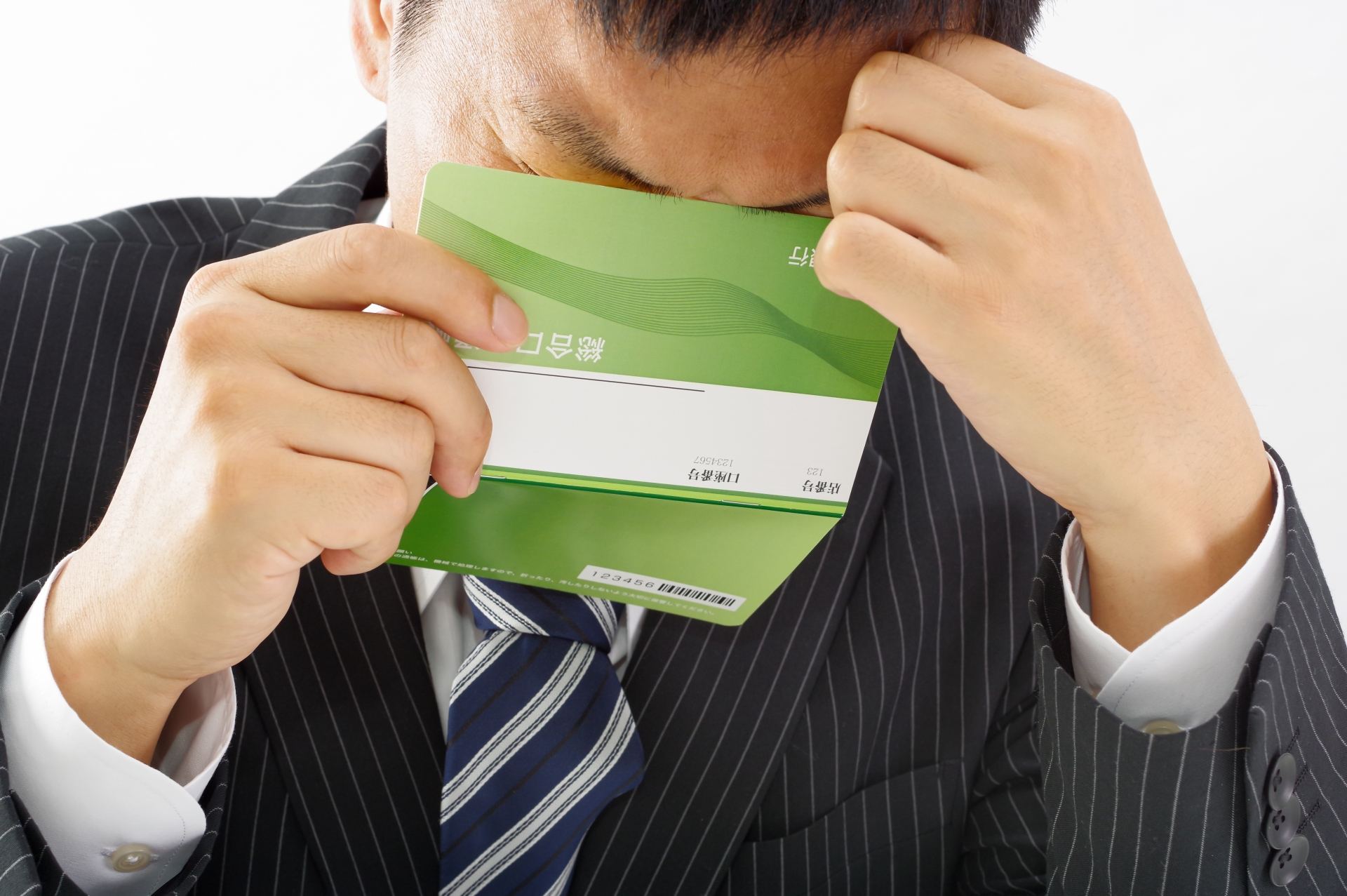 通帳を見て泣く男性