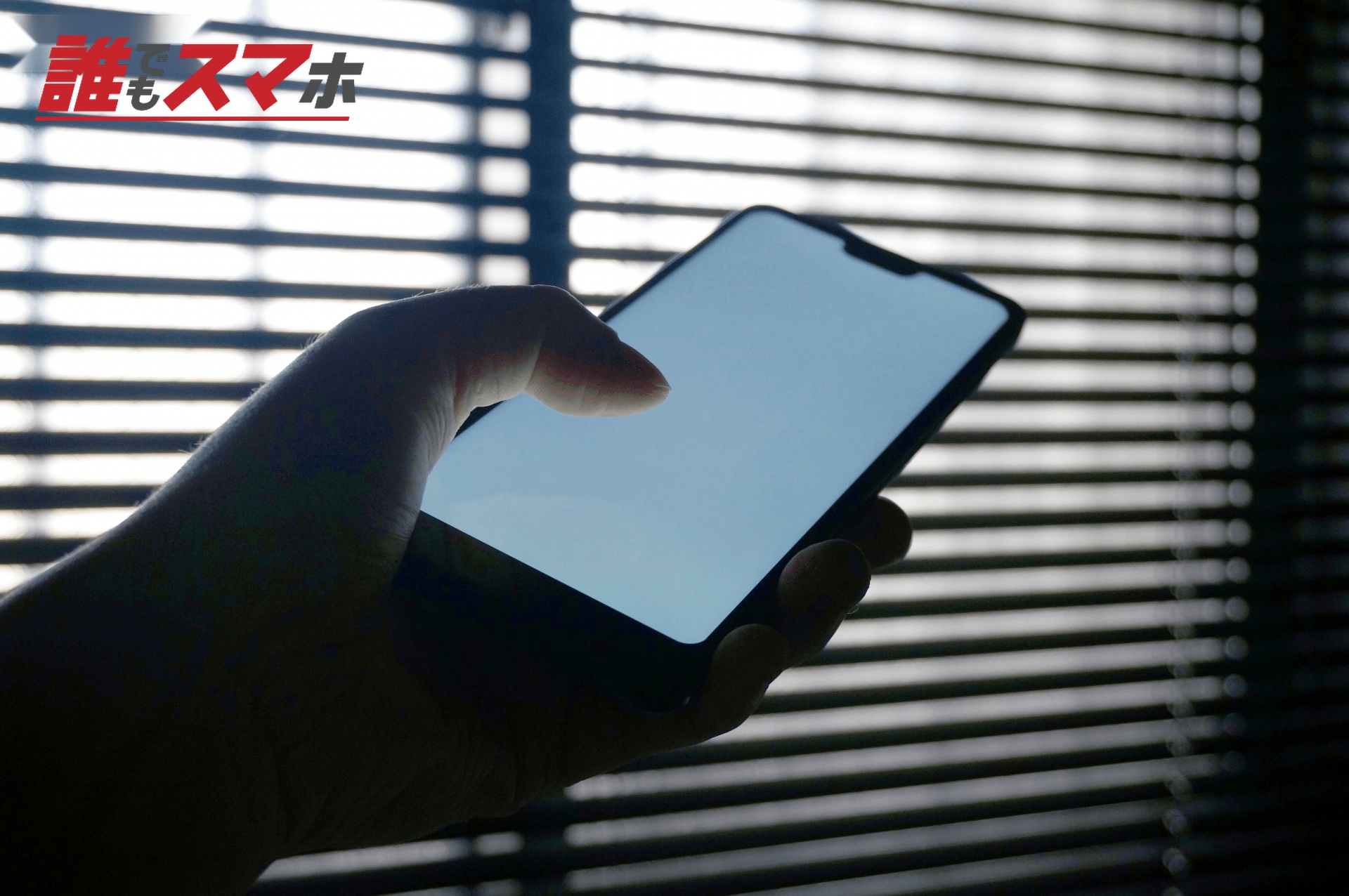 昼間の窓際の室内でスマホを見る