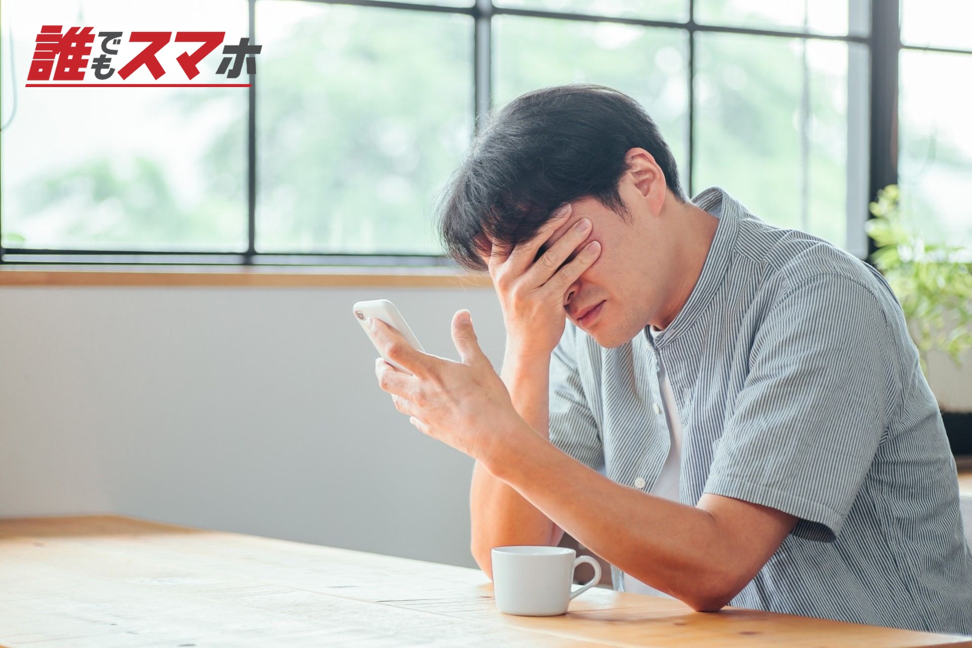 スマホを見て悩む男性(絶望)
