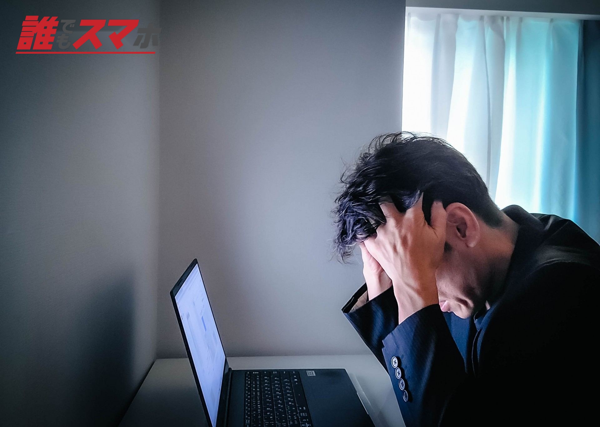 暗い部屋で頭を抱える男性
