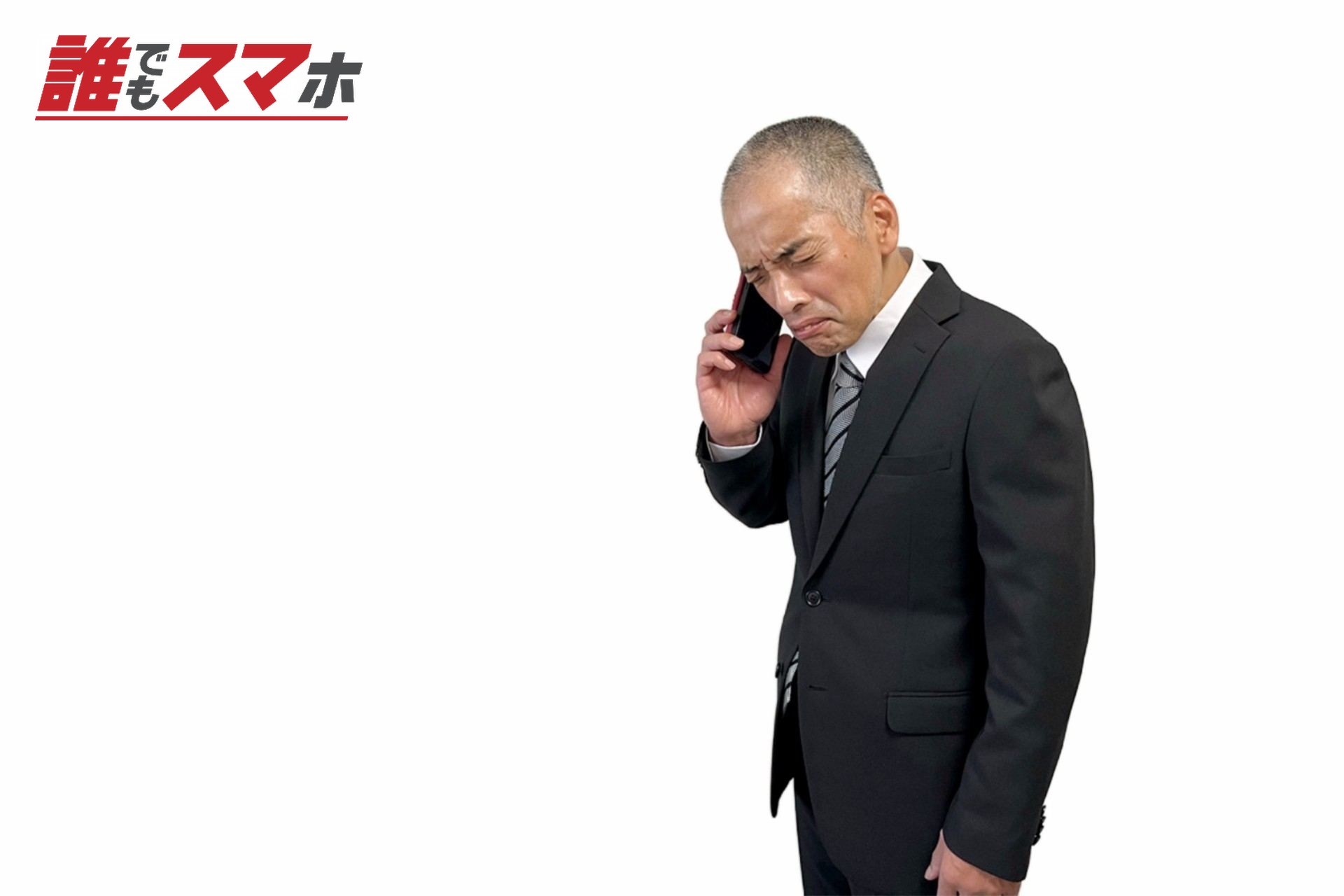 スマホの電話でクレーム対応するスーツ男性