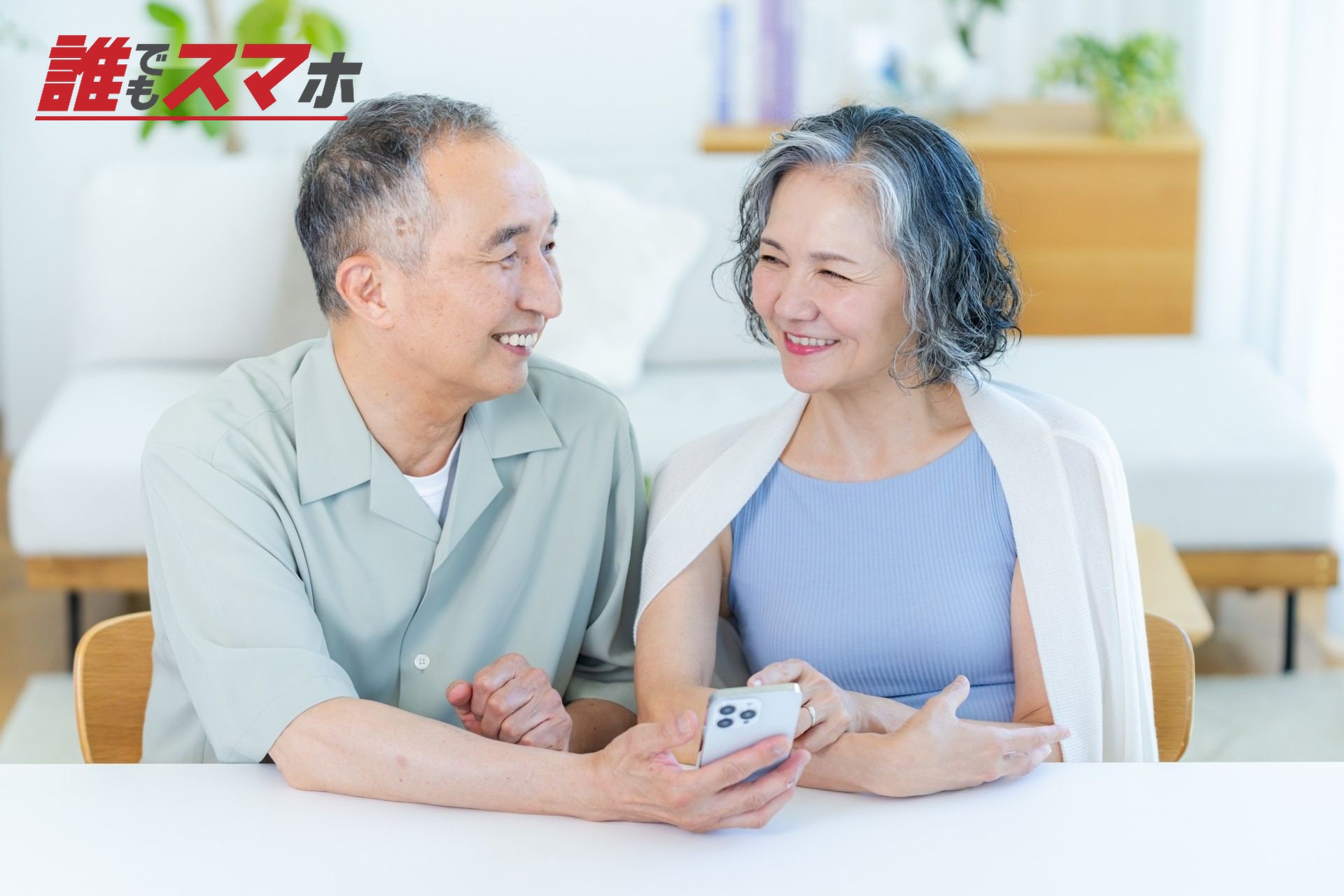 リビングでスマホを見るシニア夫婦