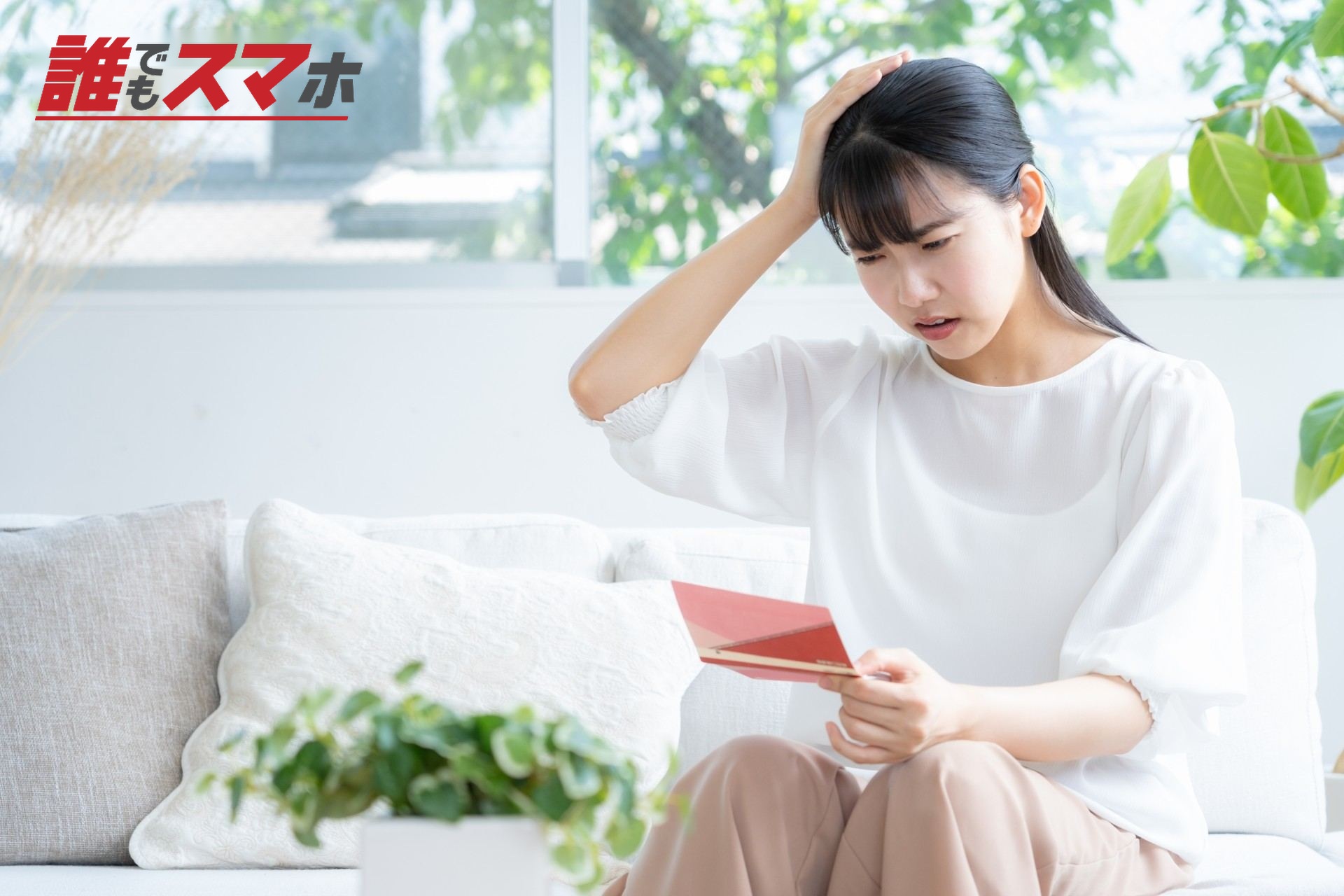 リビングで貯金通帳を見る若い女性