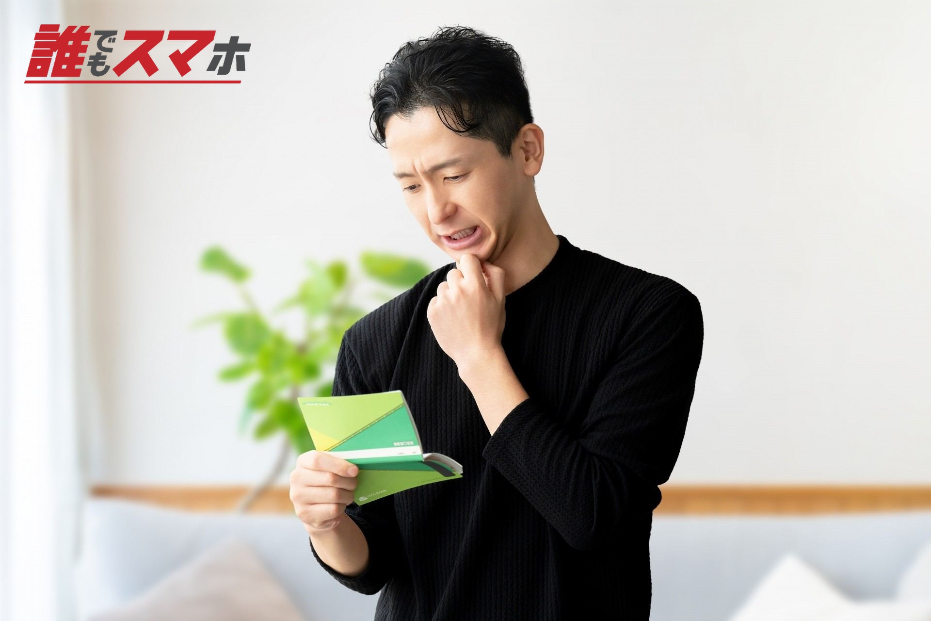 通帳を見て考える男性