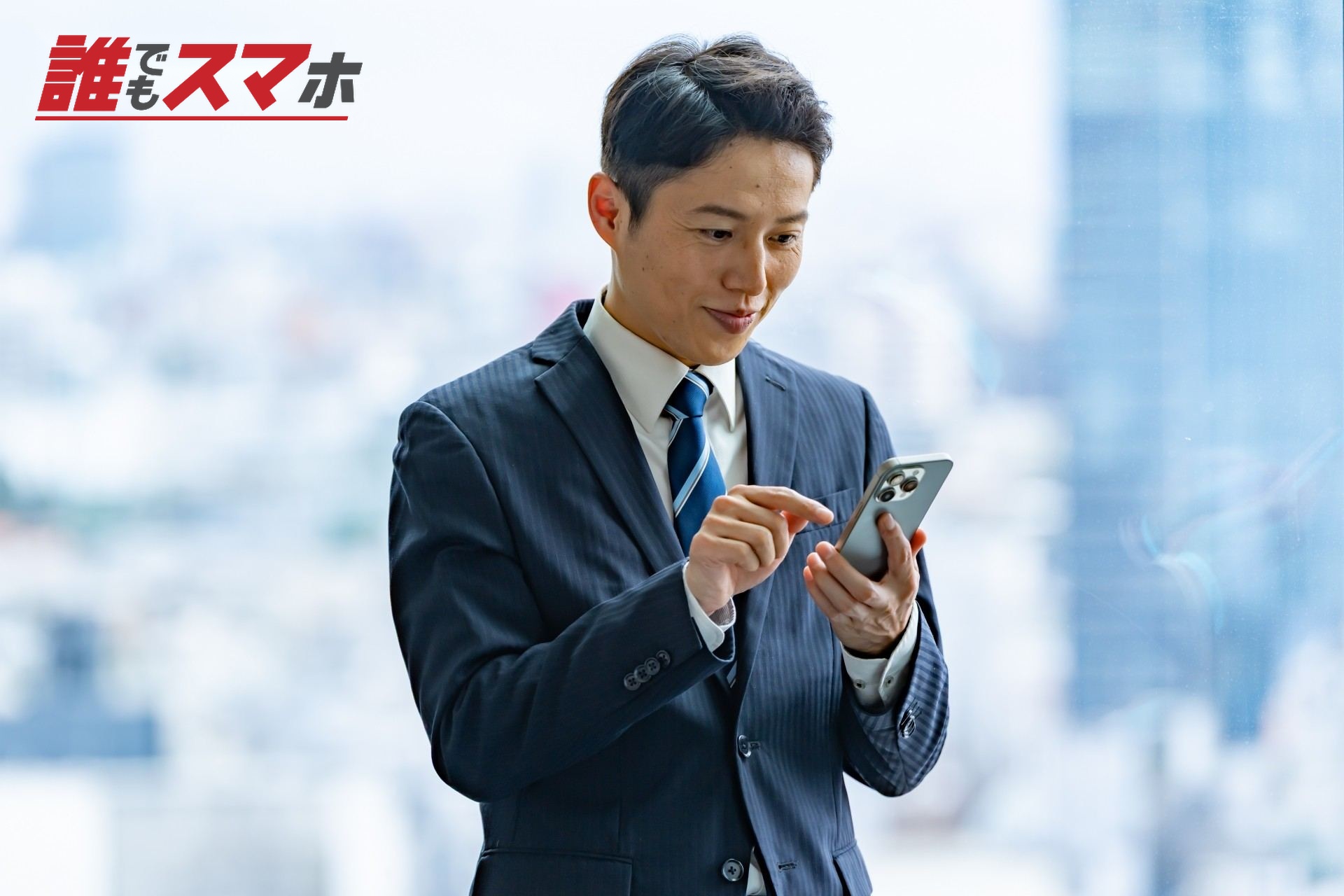 高層ビルで携帯を触るビジネスマン