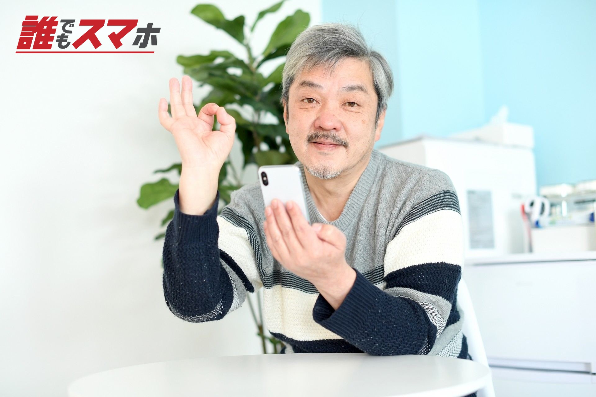 OKサインを出してスマホを操作する白髪男性
