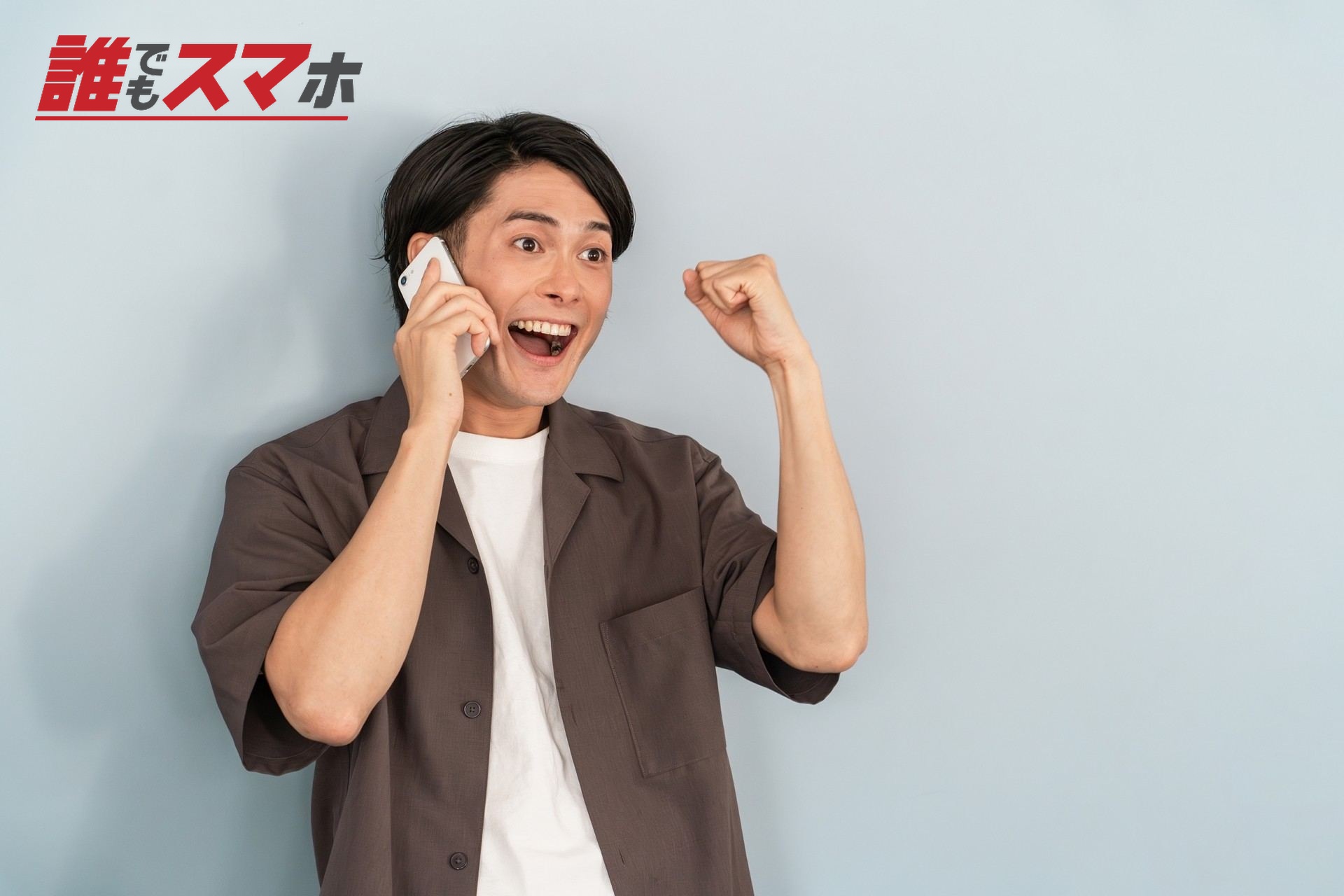 スマホで通話する喜ぶ男性・ガッツポーズ