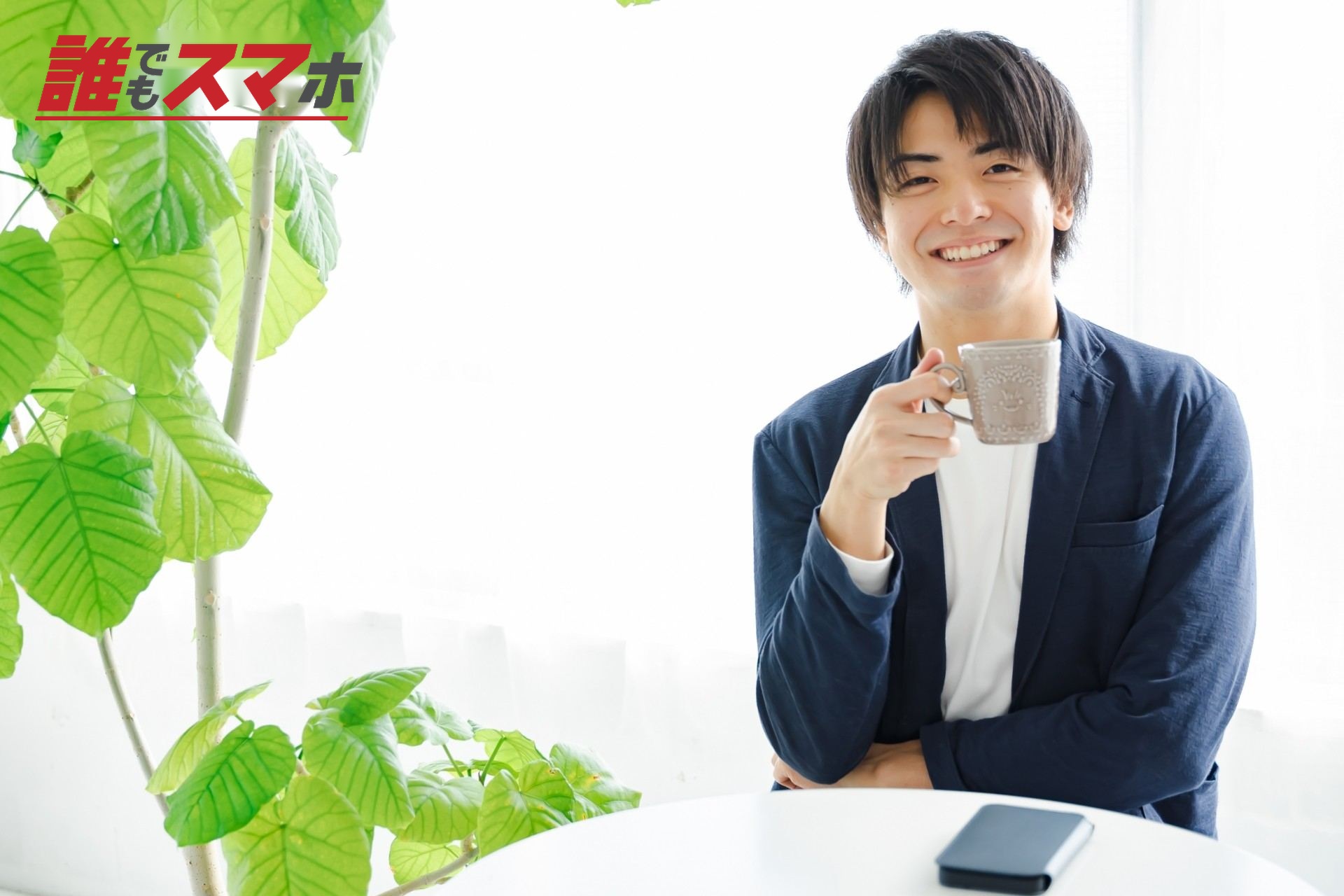 飲み物を持ってこちらを見る笑顔の男性