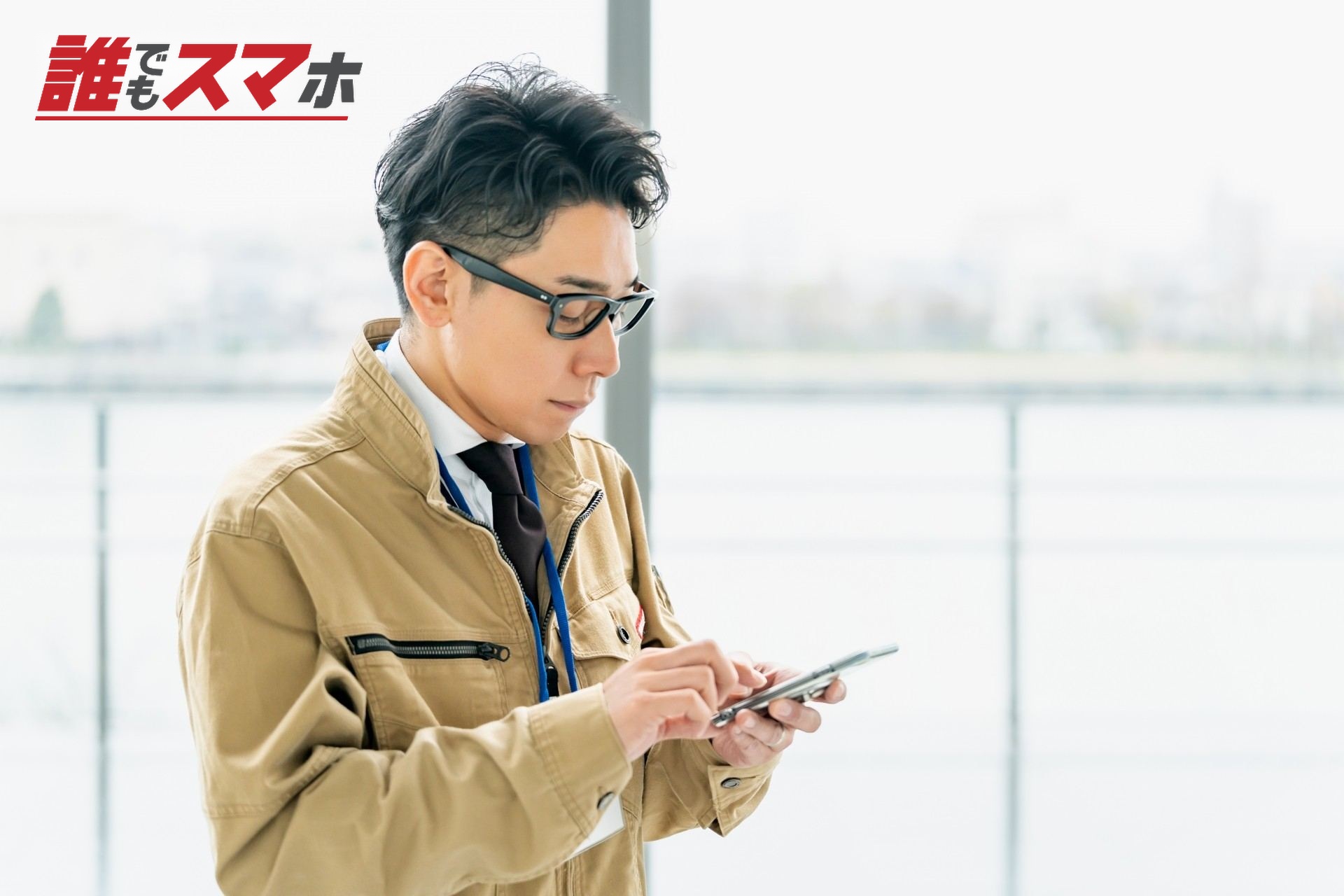 携帯電話を確認する作業服の男性