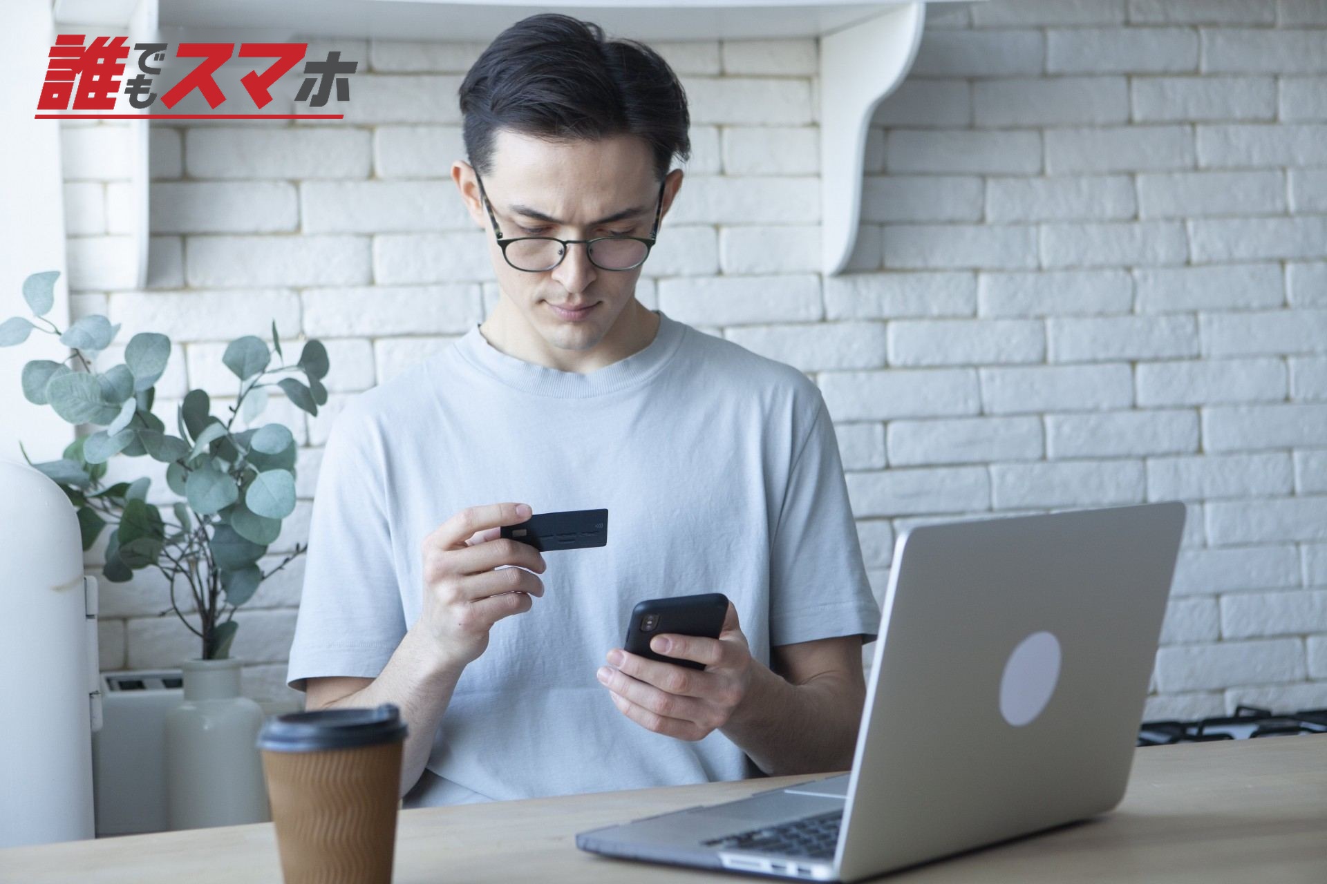 クレジットカードを見ながらスマホで入力す男性