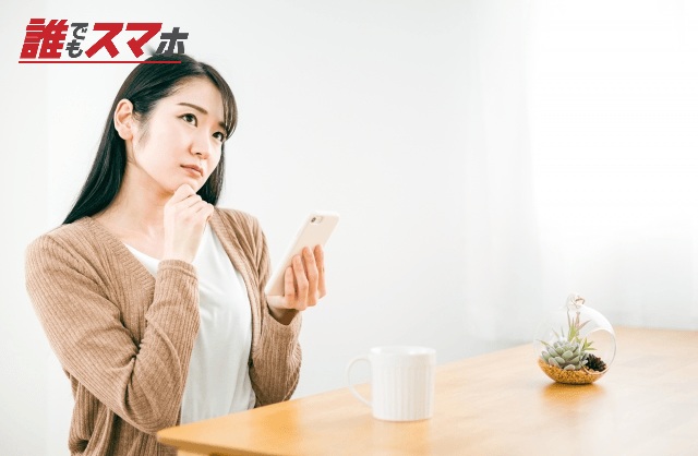 家でスマホのアプリを使いながら考える女性