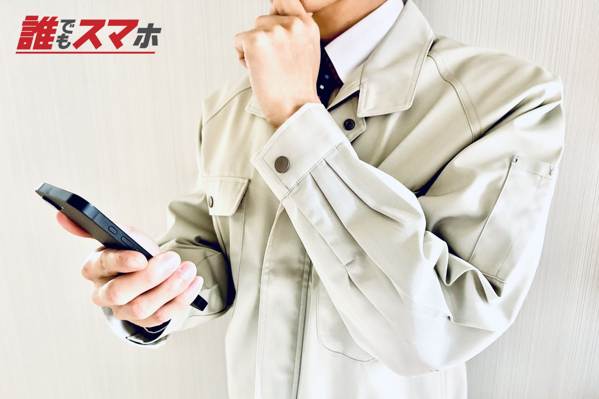 スマホを見て悩む作業着姿の男性