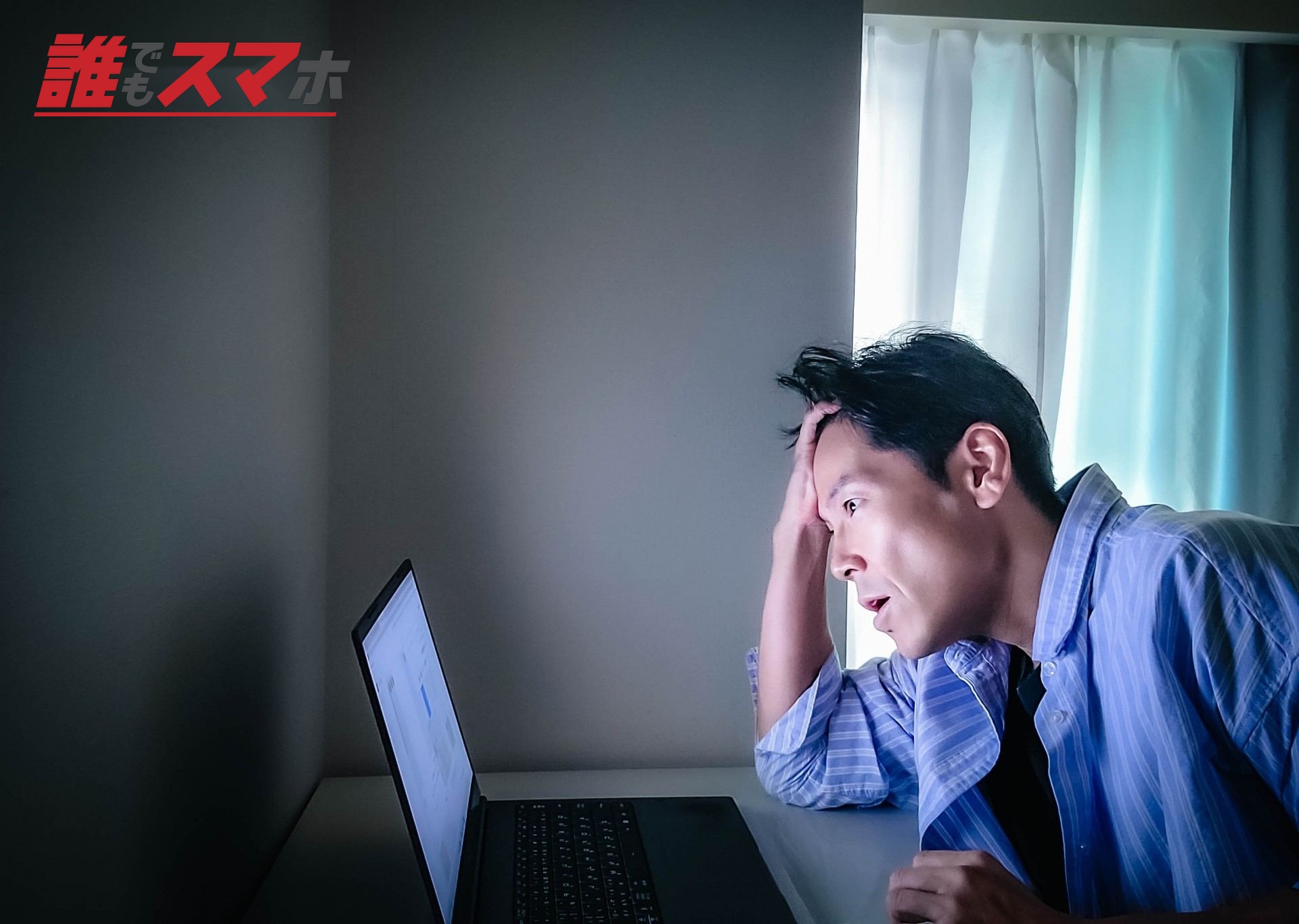 暗い部屋で悩んでる男性