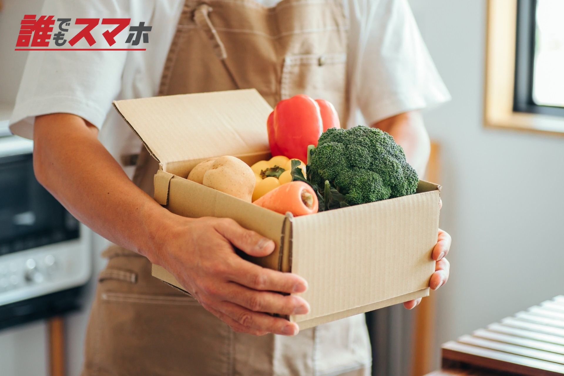 ダンボールに入った野菜を持つ男性
