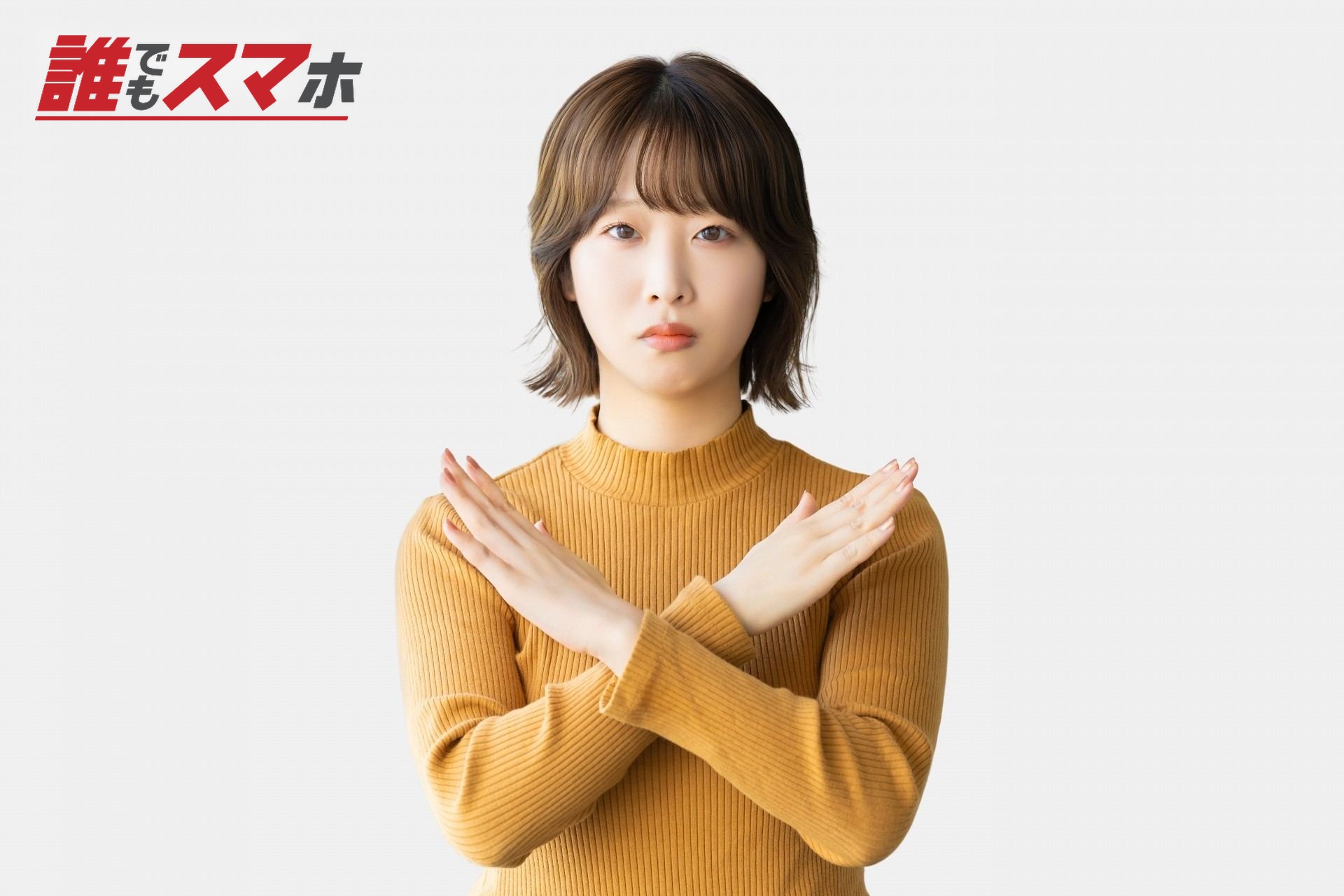 手でバツのポーズをする困った表情の女性