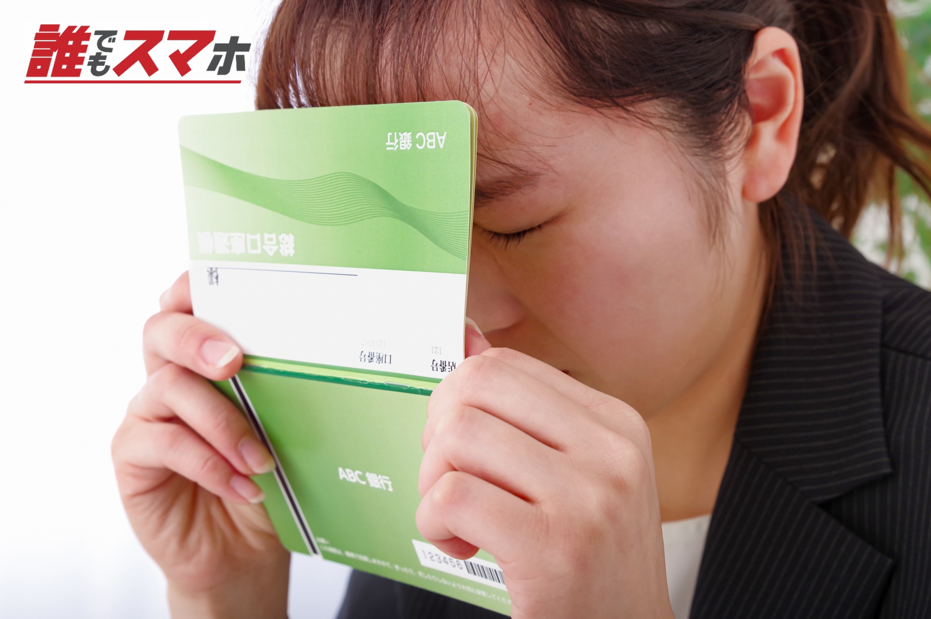 通帳で顔を隠す女性