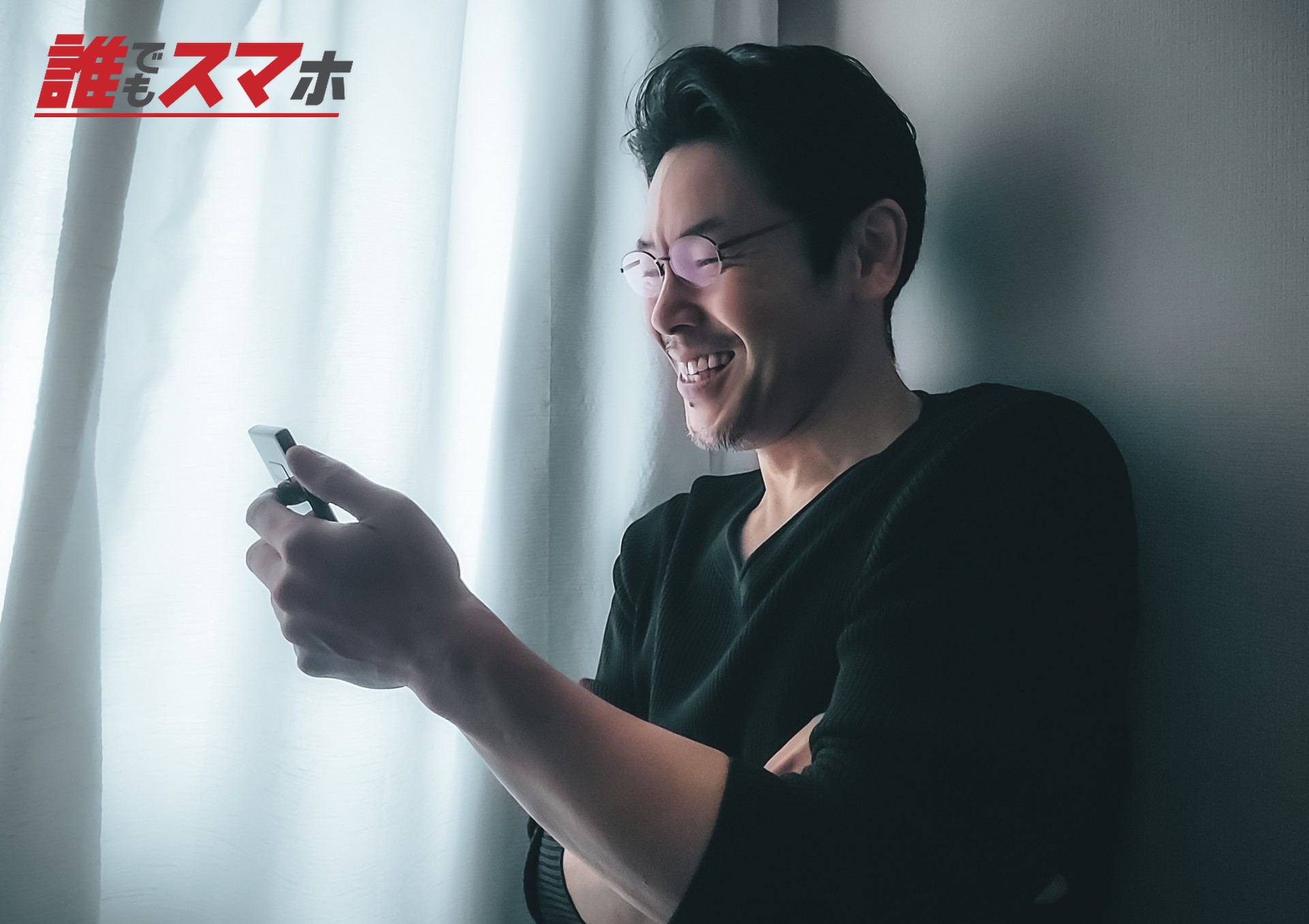 笑みを浮かべてスマホを持つミドルの男性