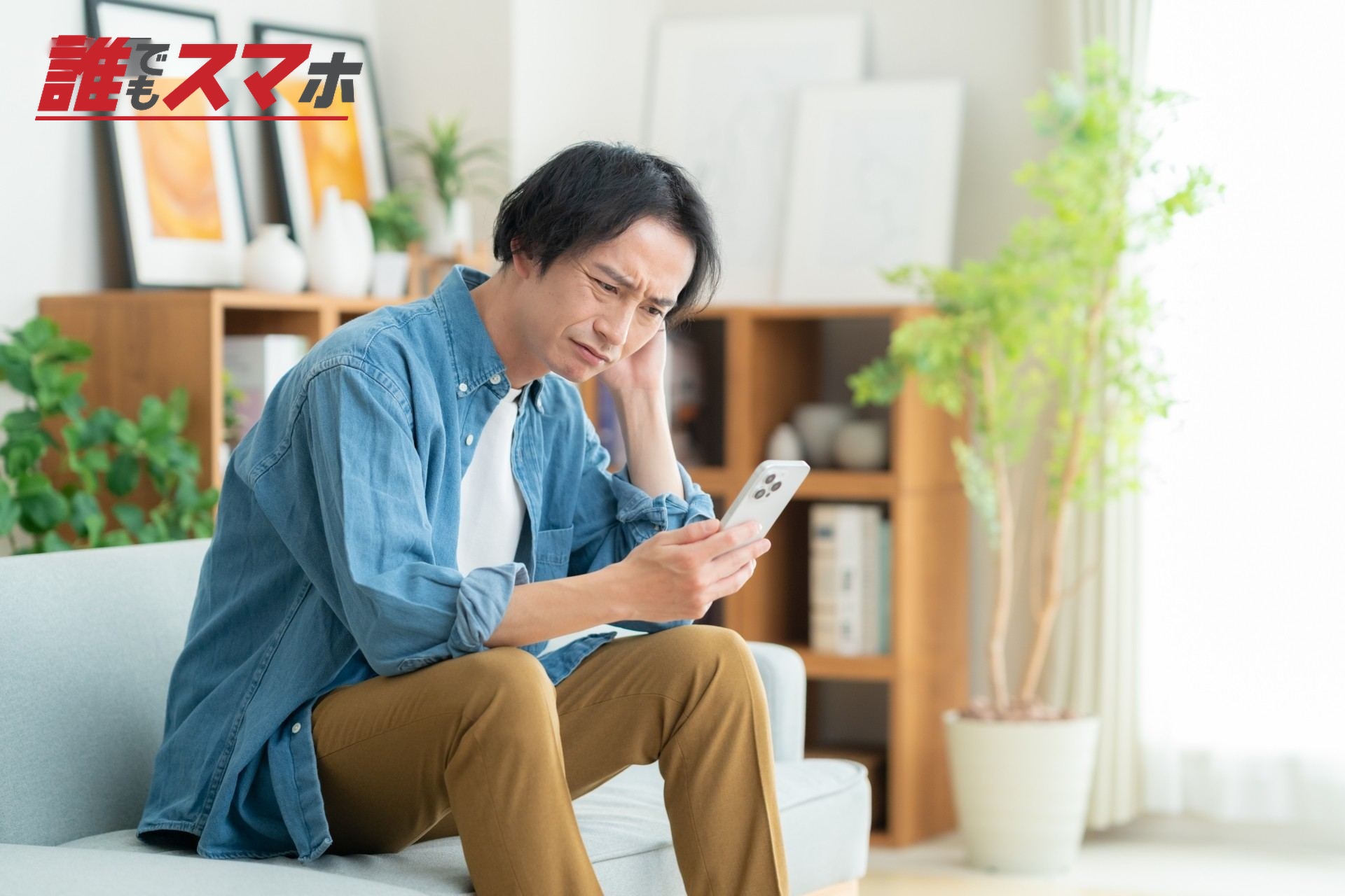 リビングでスマホを見る若い男性