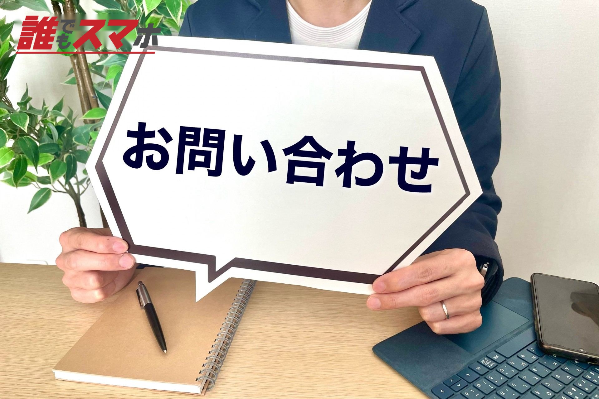 お問い合わせの札を持つ男性の手元