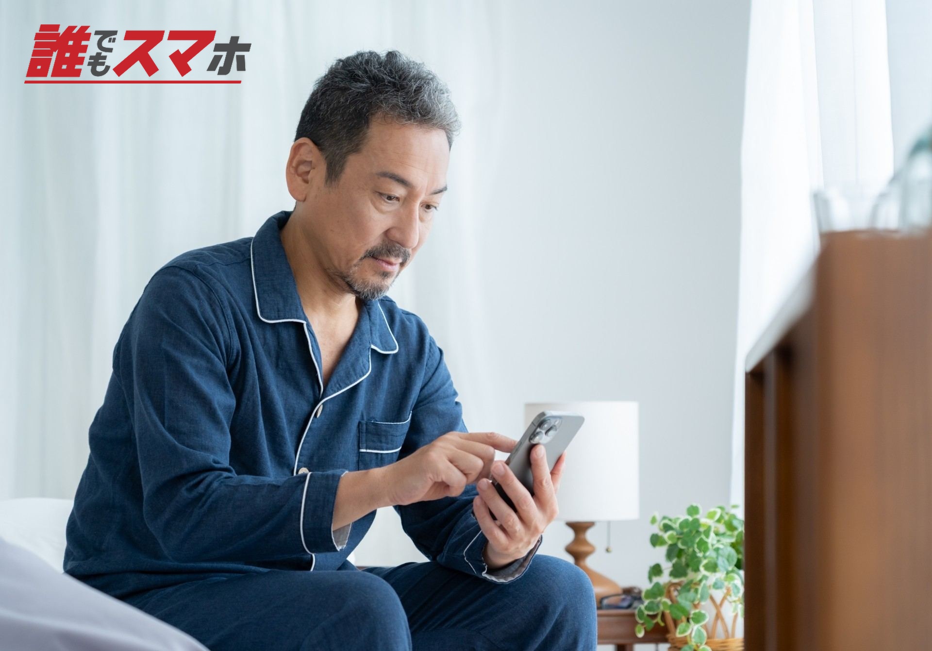 寝室でスマホを見るミドルの男性