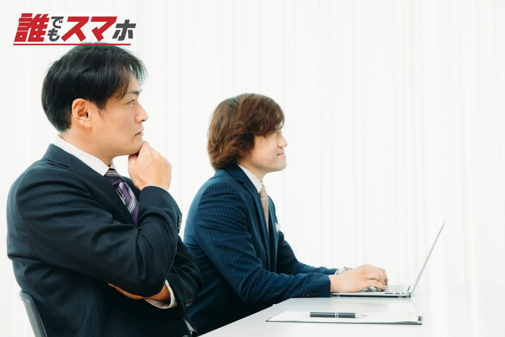 机に座るスーツ姿の男性二人