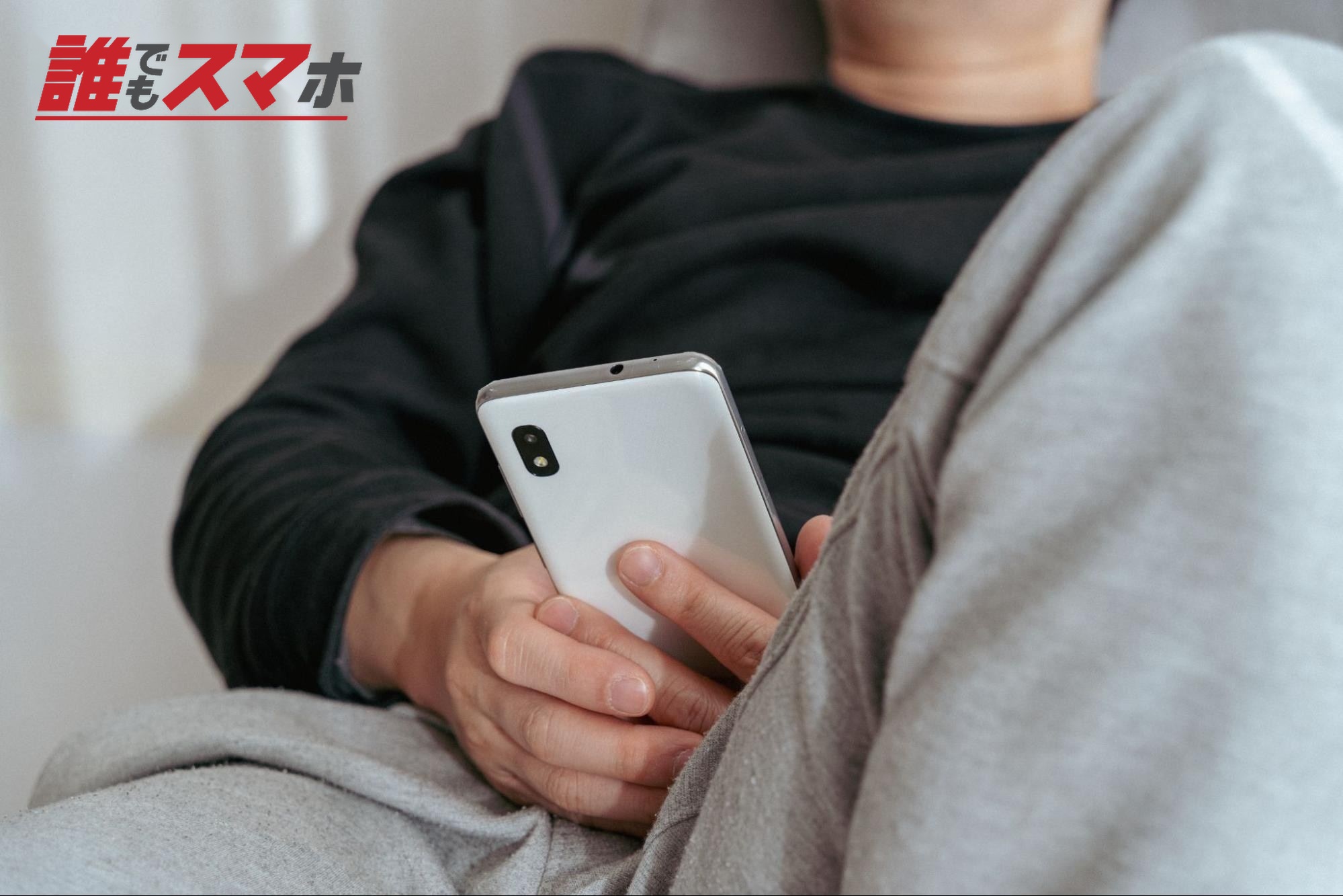 ソファーでスマホを見る男性