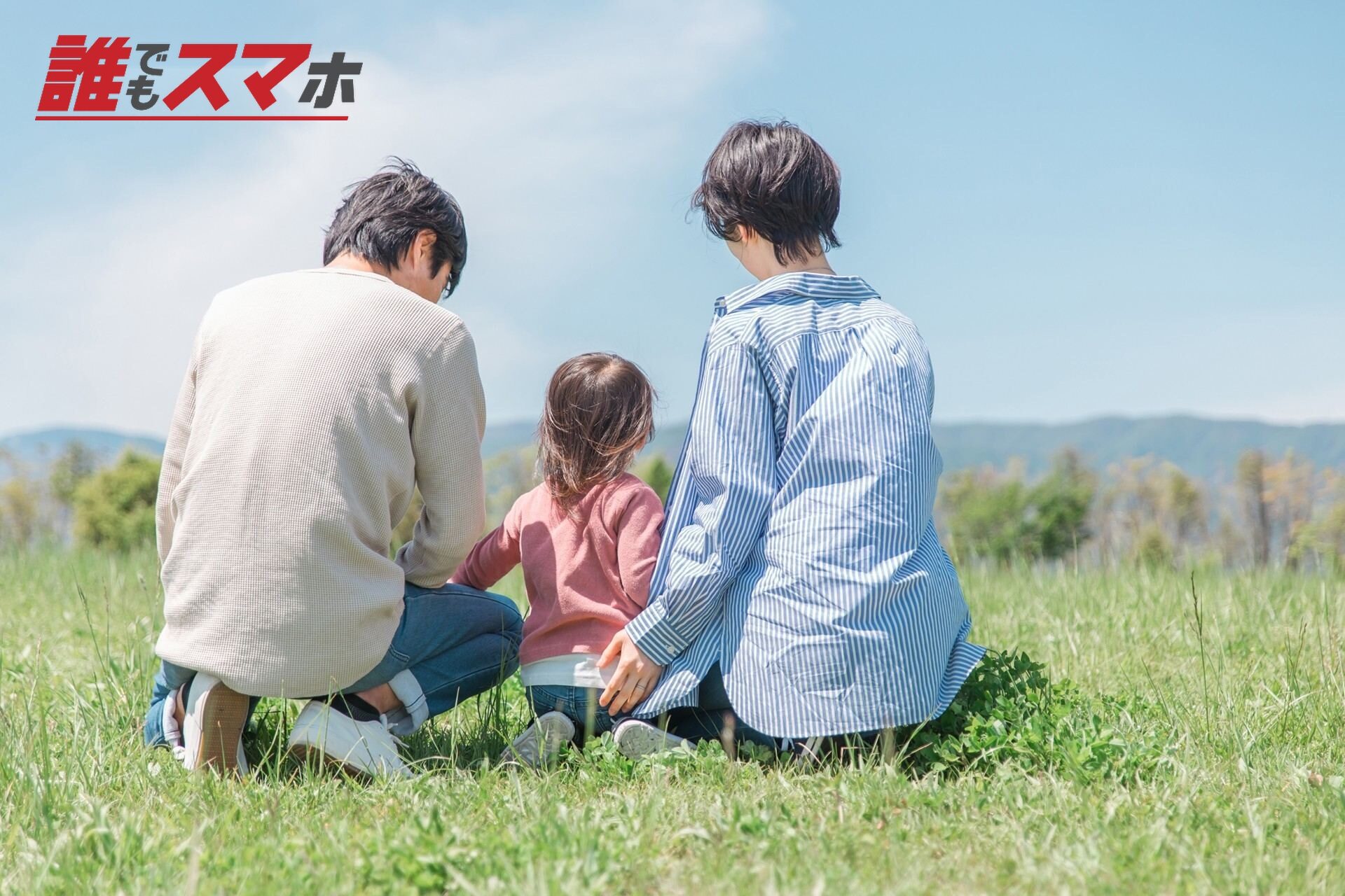 草の上に座る三人家族
