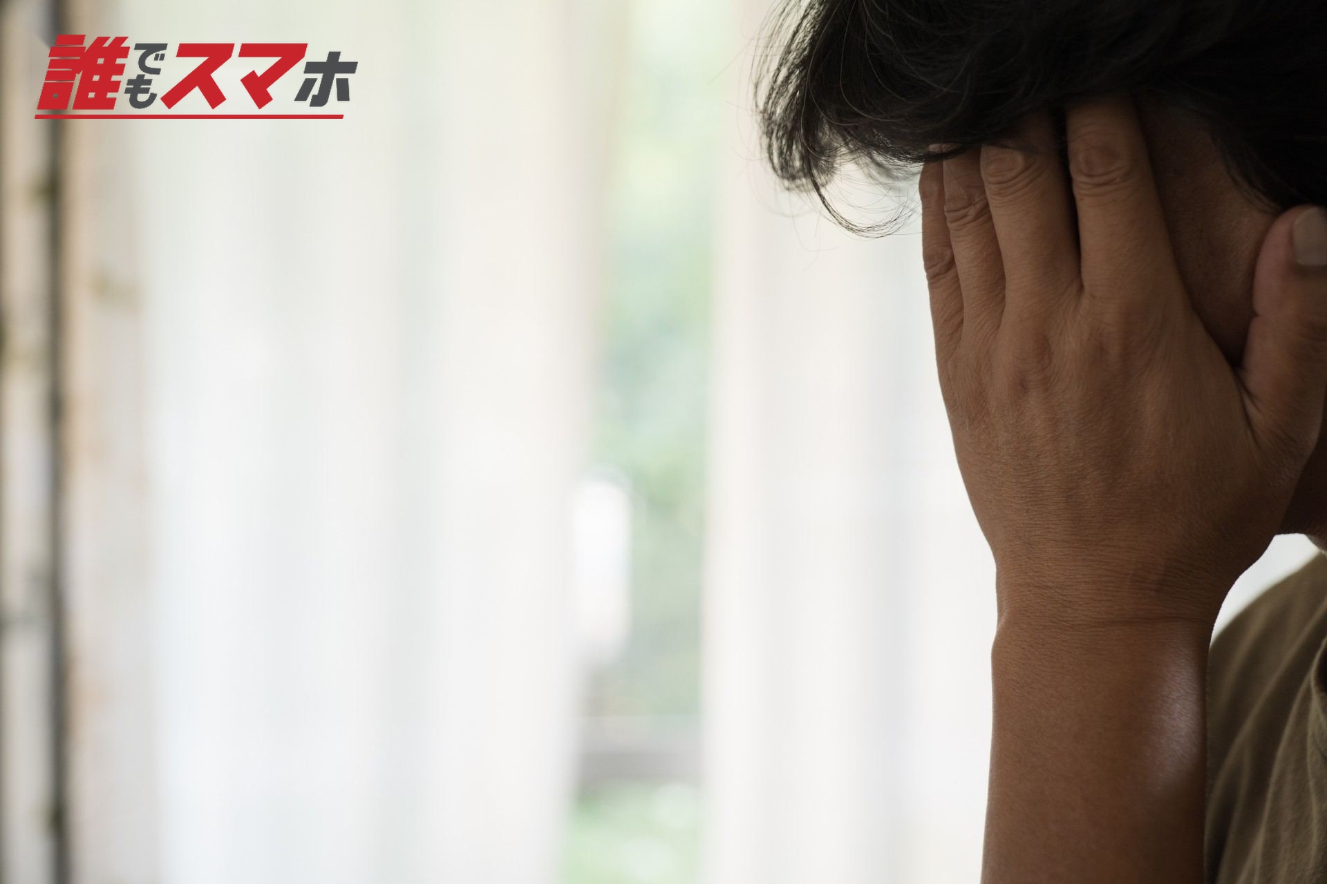 顔を覆って悩んでいる中年男性