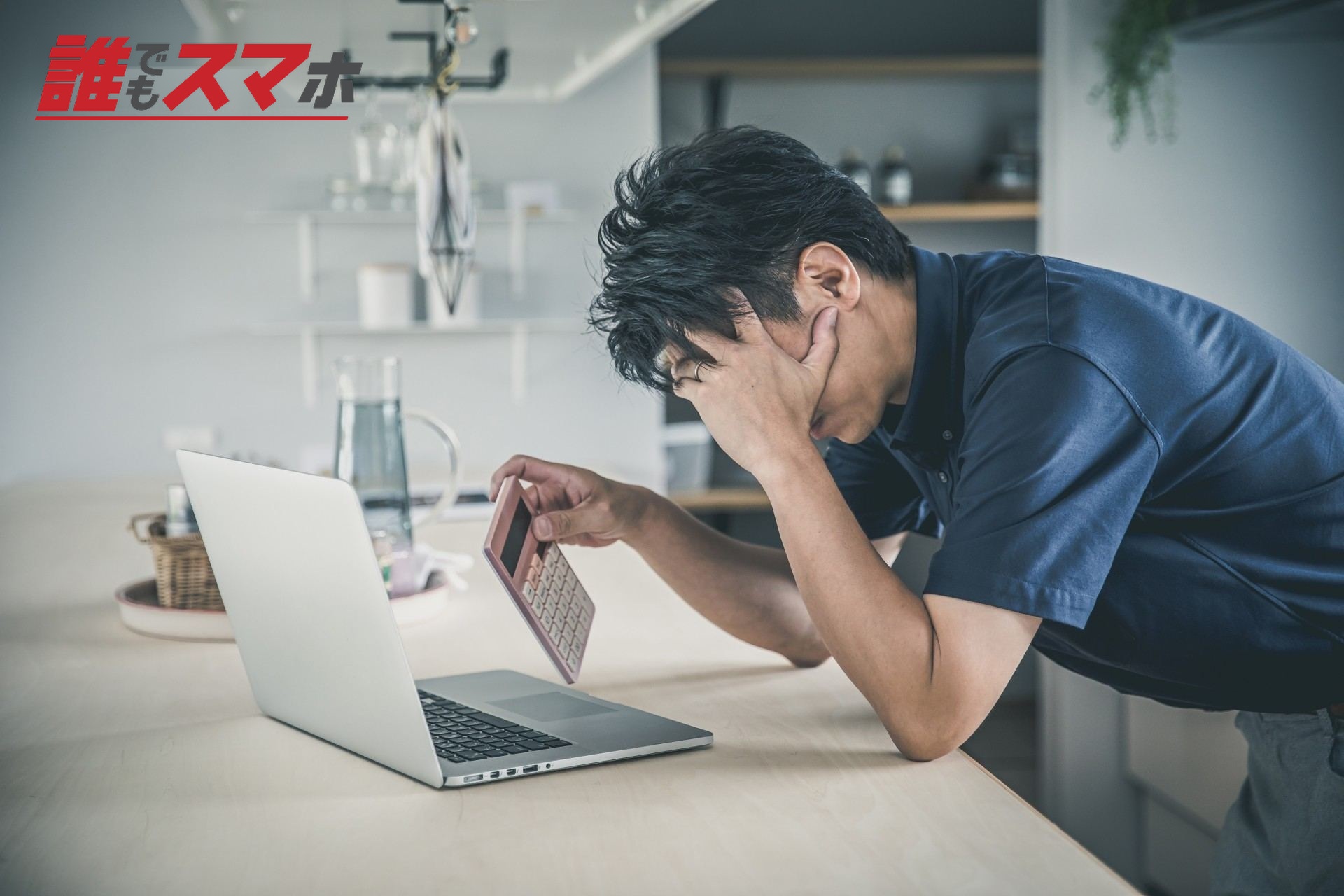 電卓を持って頭を抱える男性