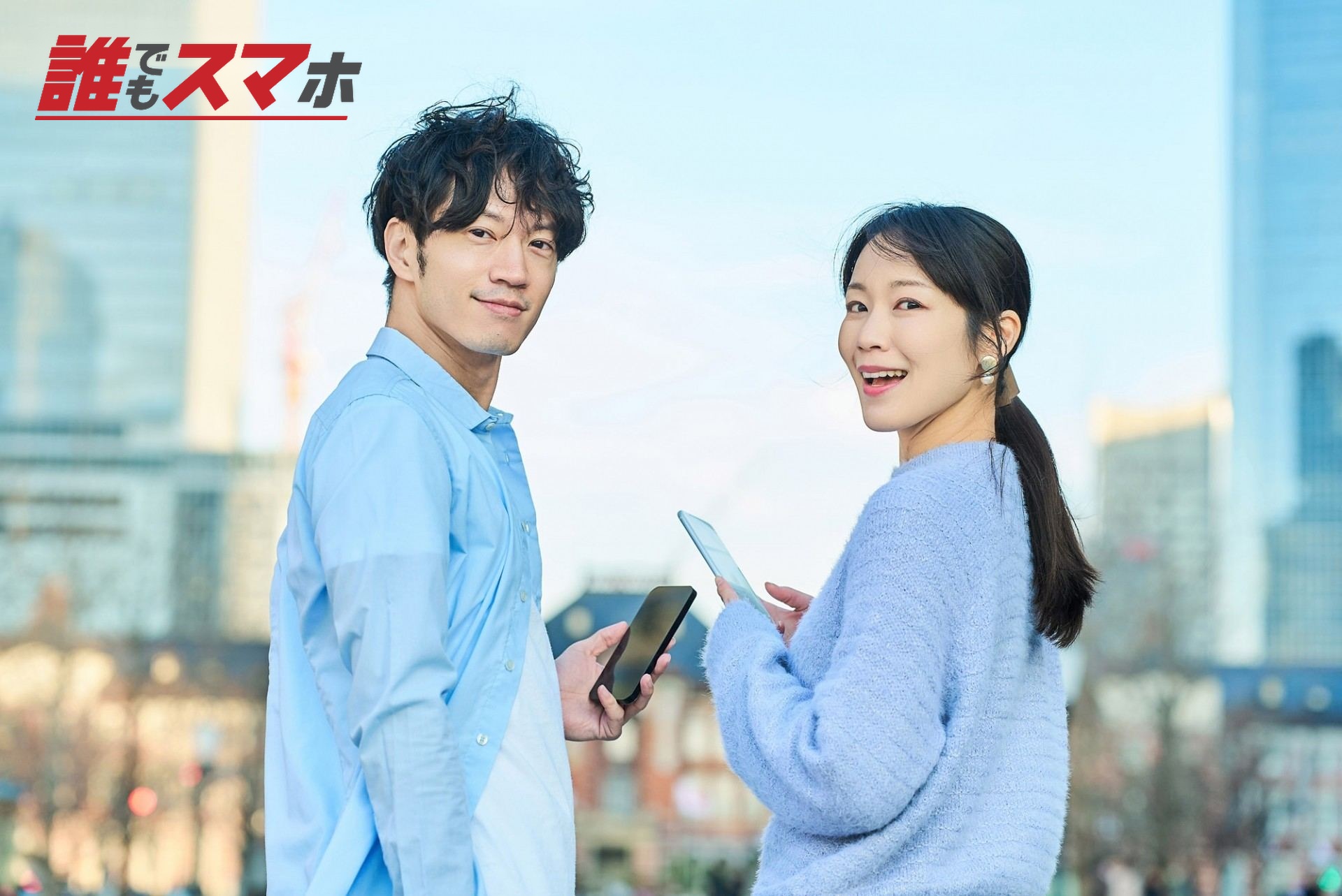 スマホを持って振り向きながらほほ笑む男女