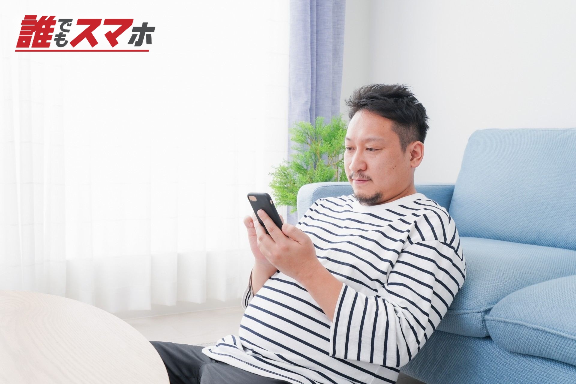 部屋でスマホを使う男性