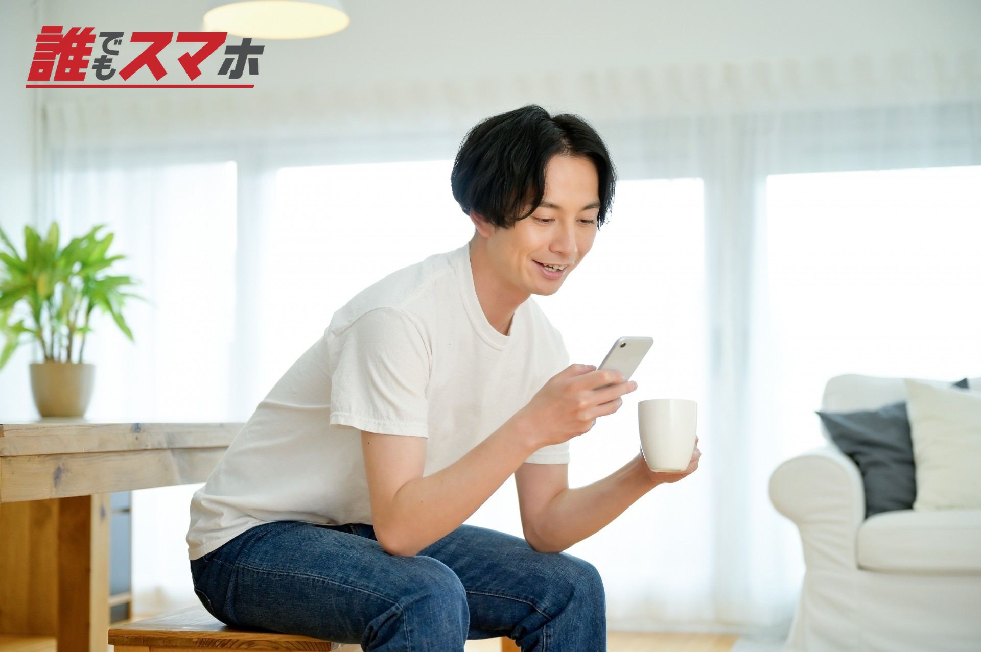 ダイニングでコーヒーを飲みながらスマホを使う男性
