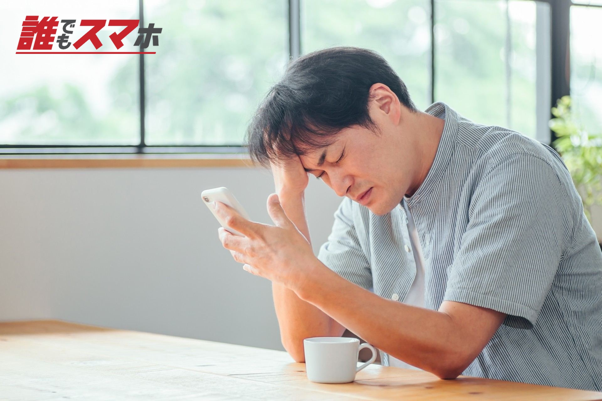 スマホを見て悩む男性