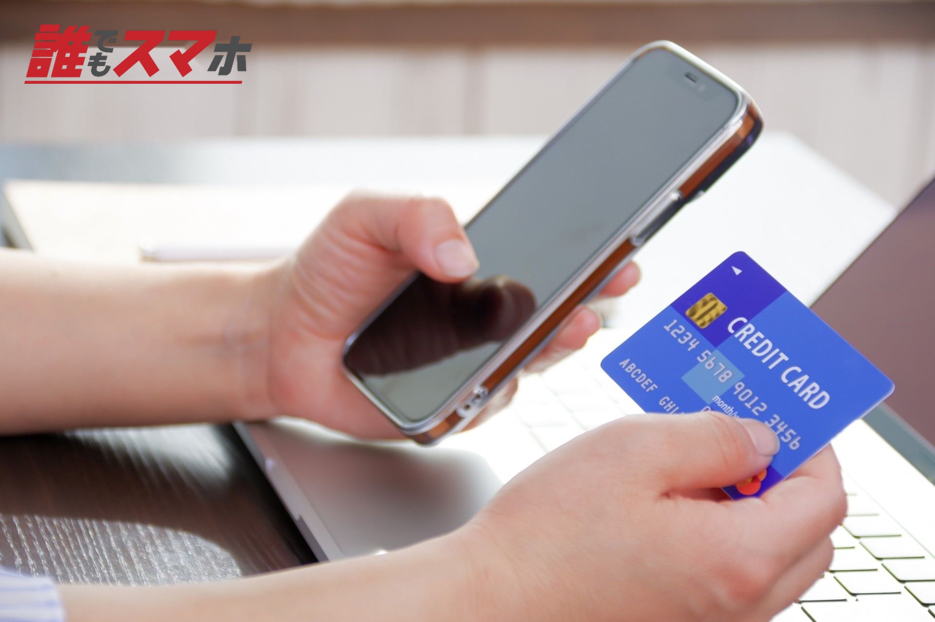 スマホとクレジットカードを持つ女性
