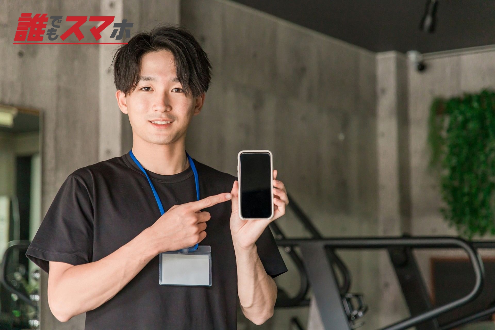 ジムでスマホを持つインストラクターの男性