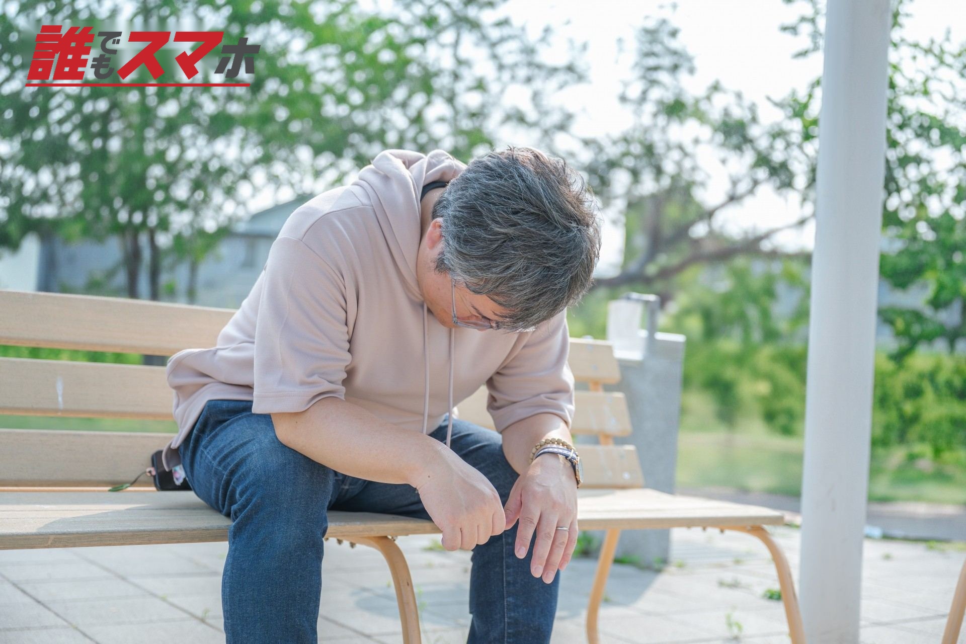 ベンチに座り下を向く男性