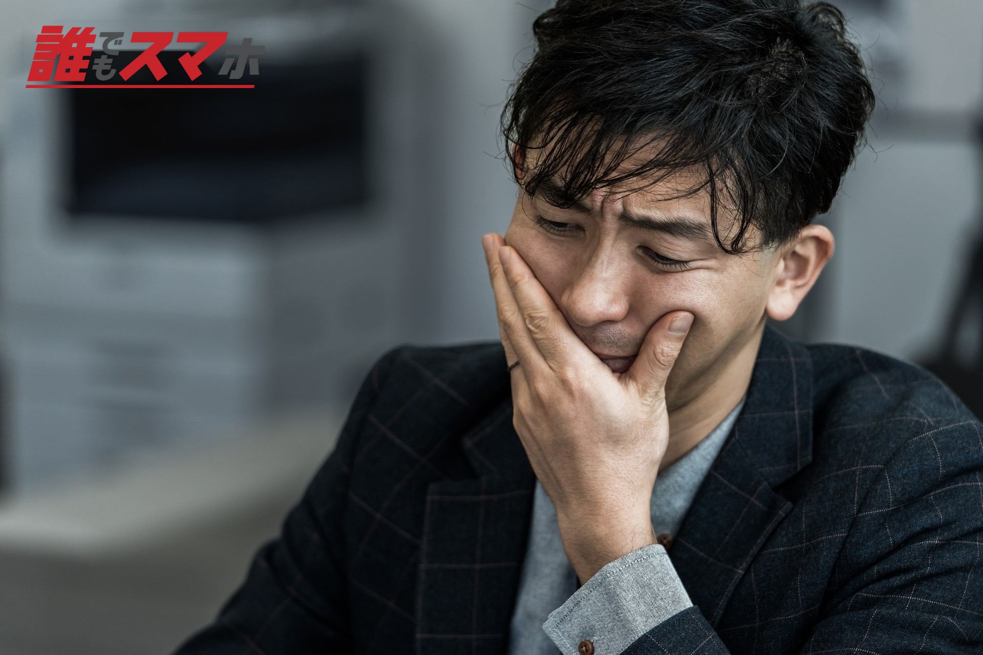 手で口元を押さえ苦悩する男性