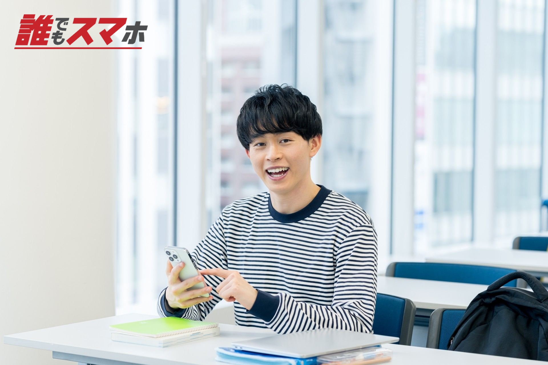 教室でスマホを見る大学生
