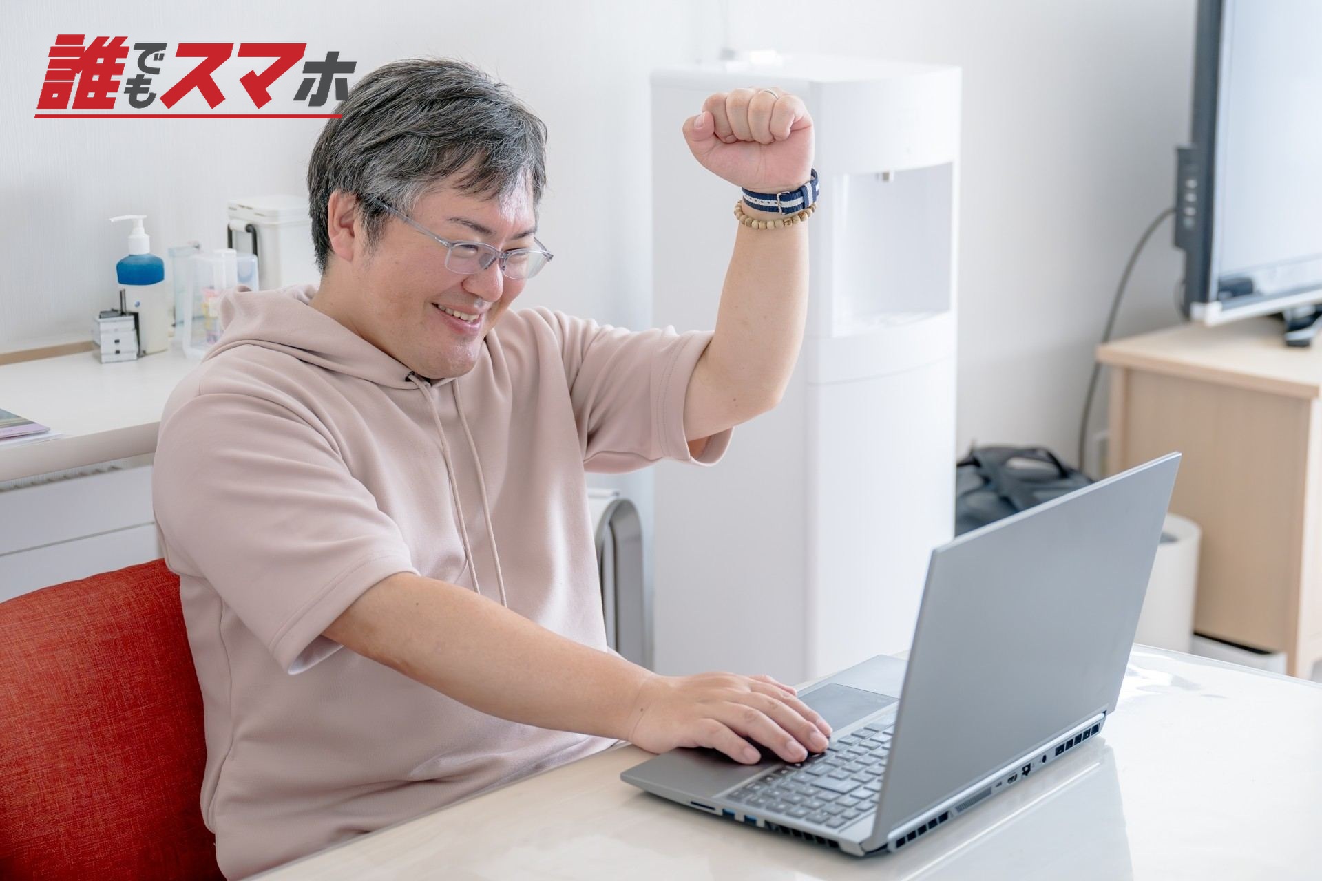 パソコンを見て笑顔でガッツポーズを作る男性