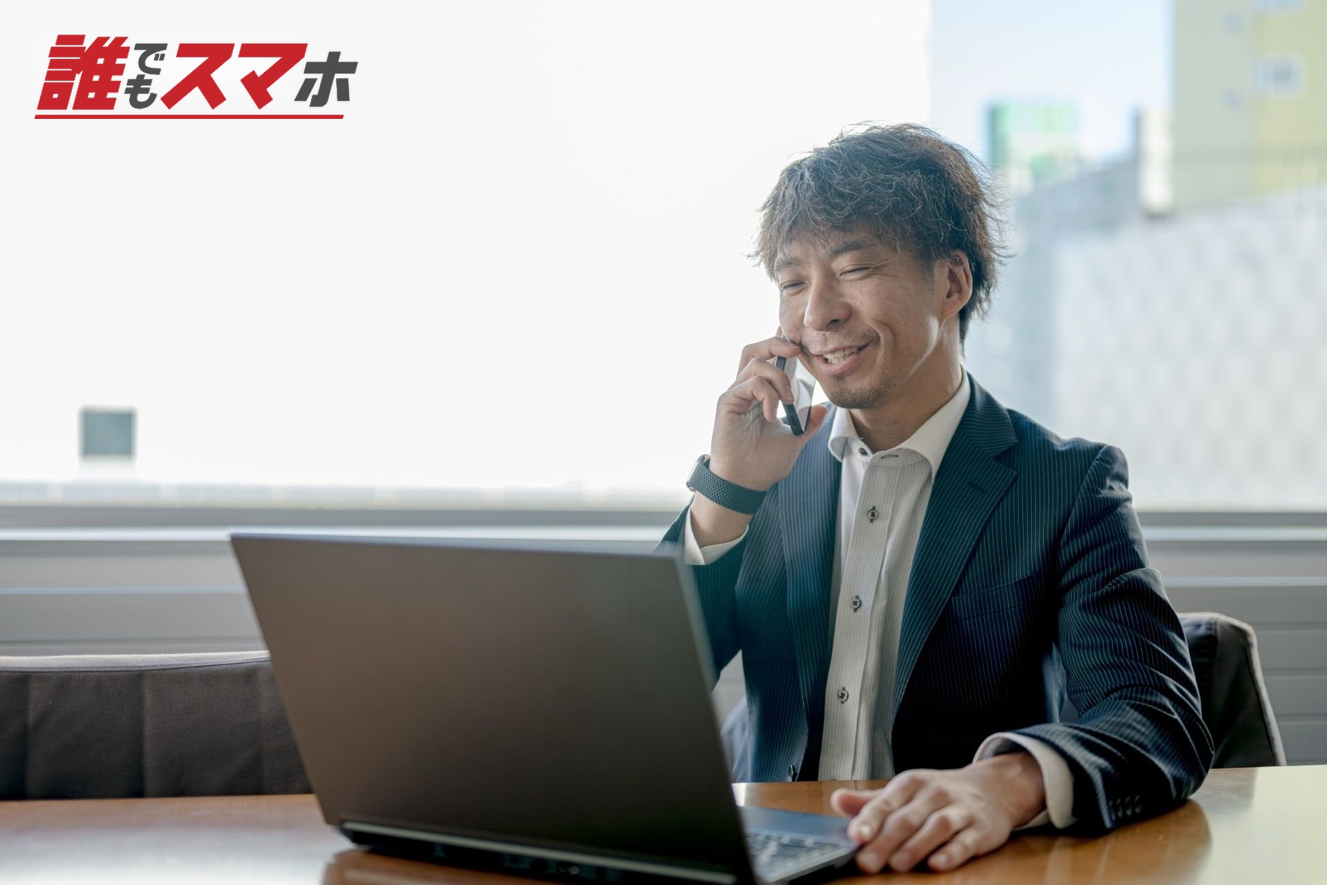 パソコンを見ながらスマホで通話する男性