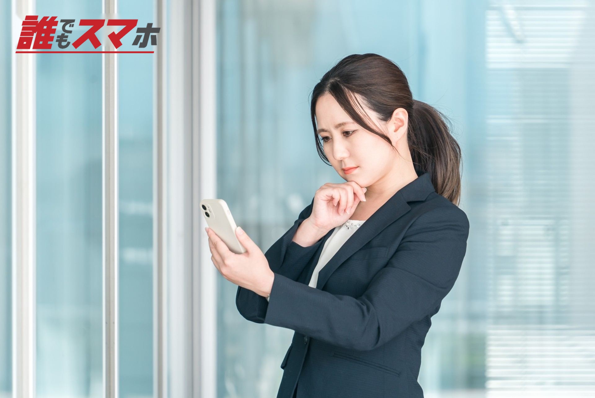 携帯電話を見ながら悩む女性