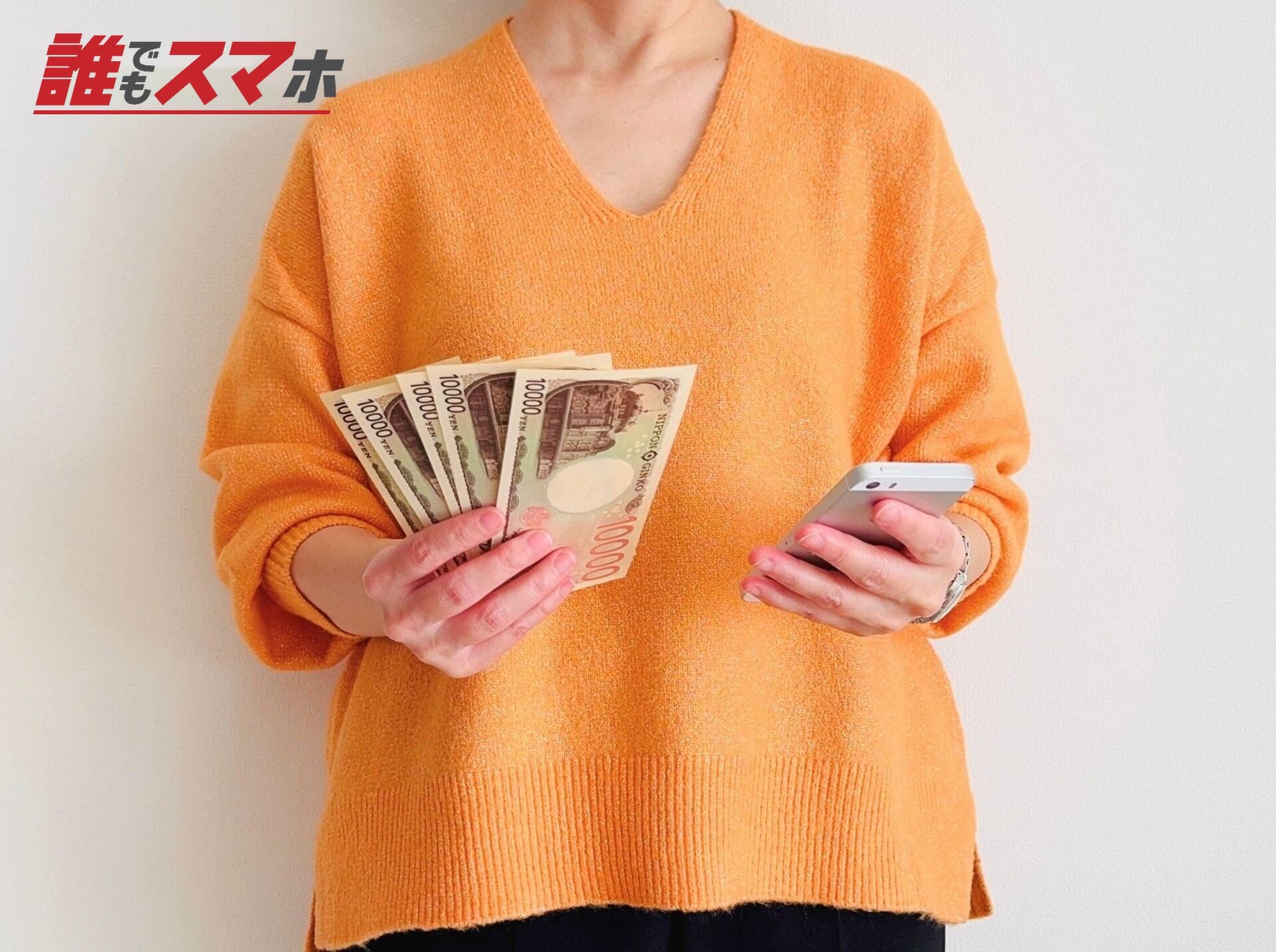 スマホとお札を手にする人