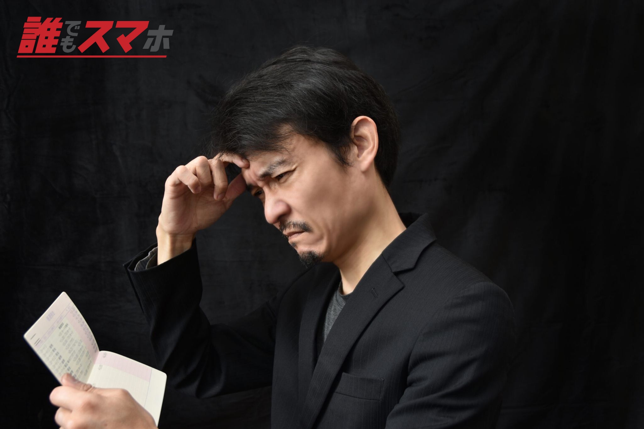 通帳を見て悩む男性