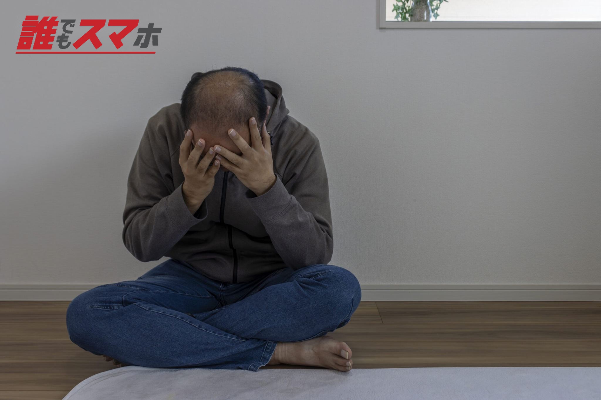 部屋で座り落ち込んでいる男性(顔無