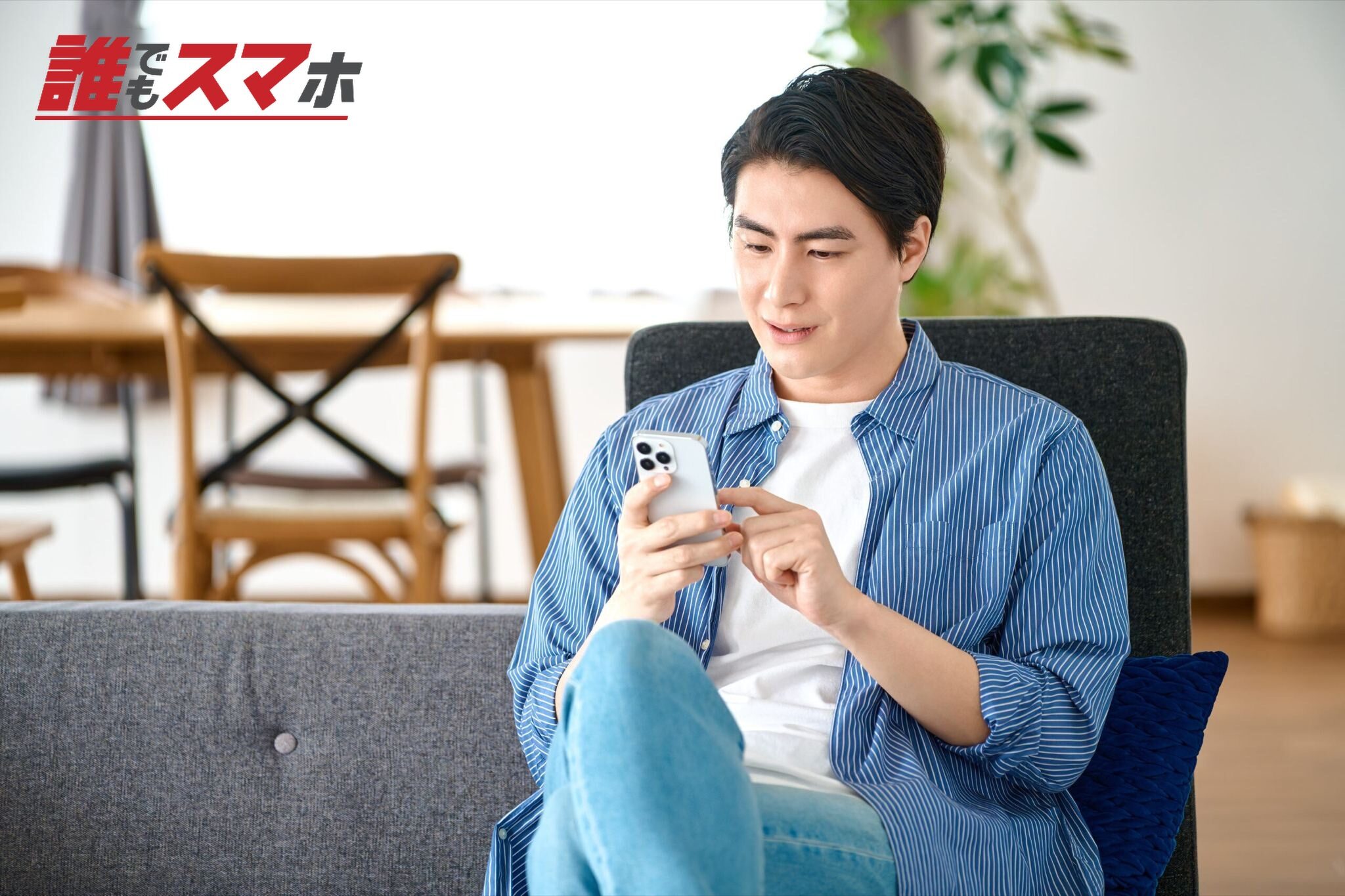 リビングのソファでスマホを操作する男性