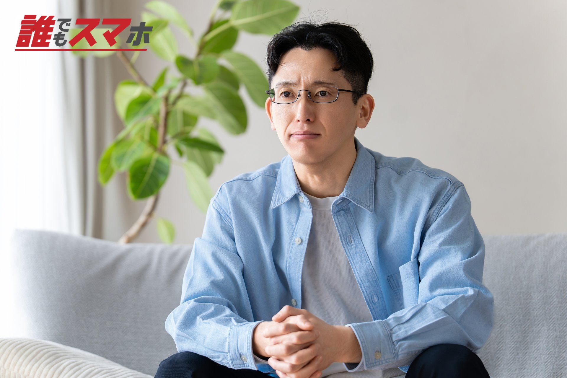 リビングのソファに座って考える男性