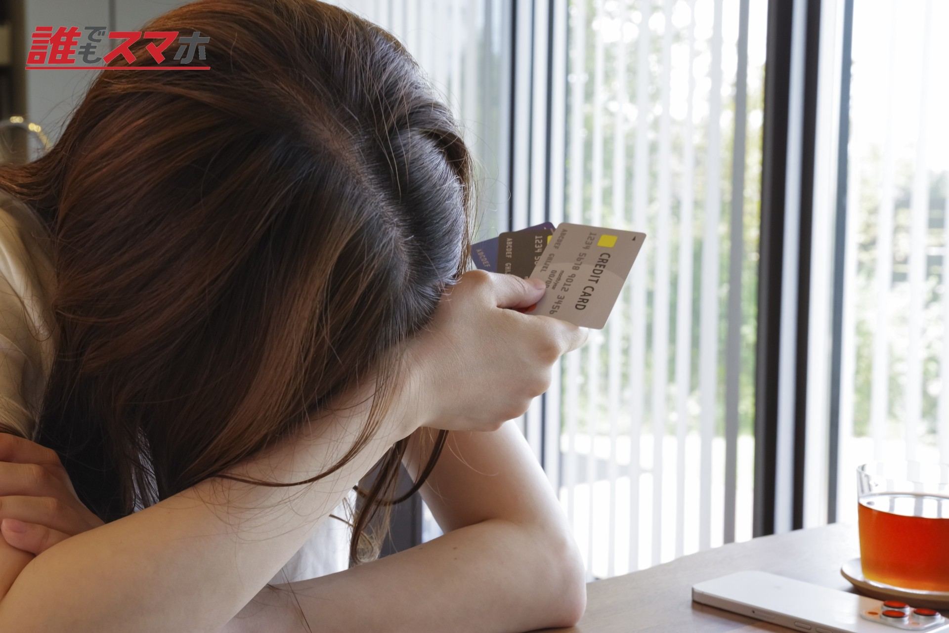 カードを持ち頭を抱える女性