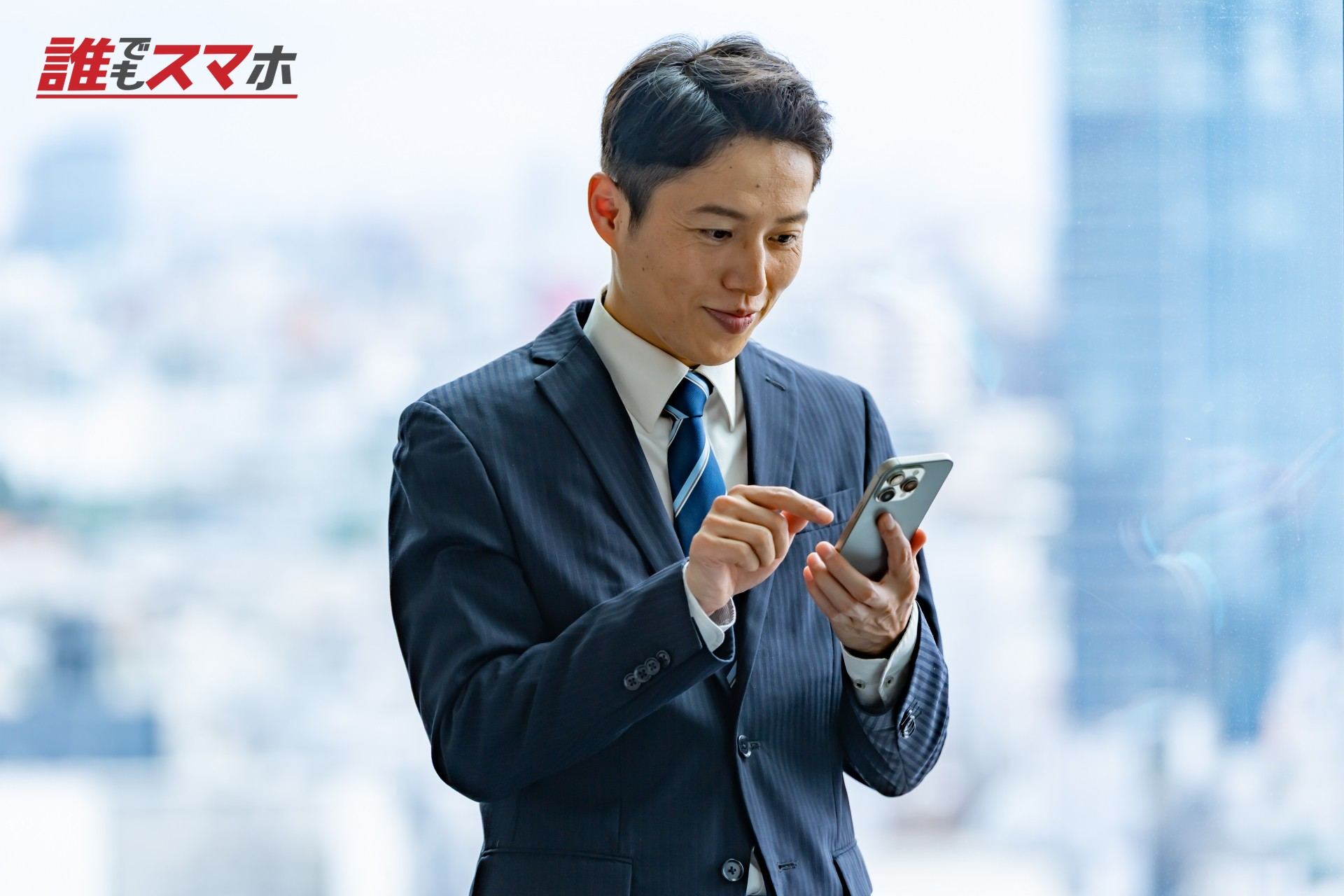 高層ビルで携帯を触るビジネスマン